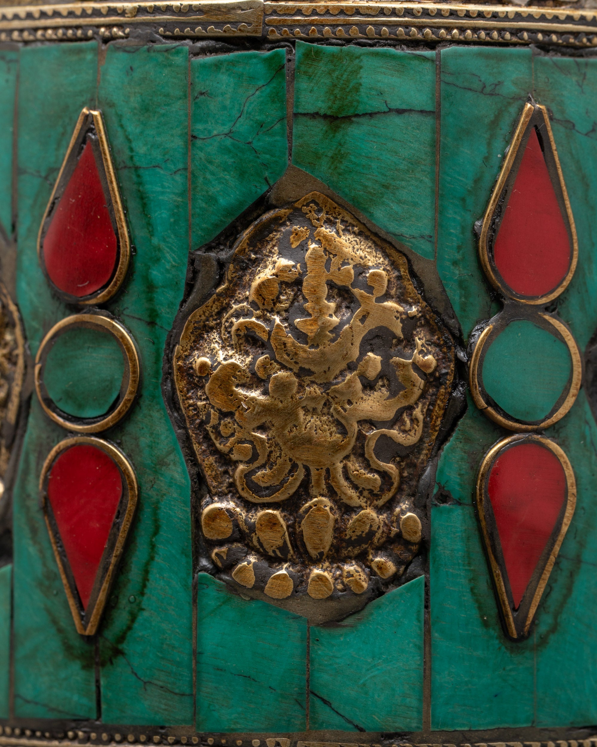 Close-up of turquoise and coral inlays on copper Auspicious Prayer Wheel with detailed mantra engravings