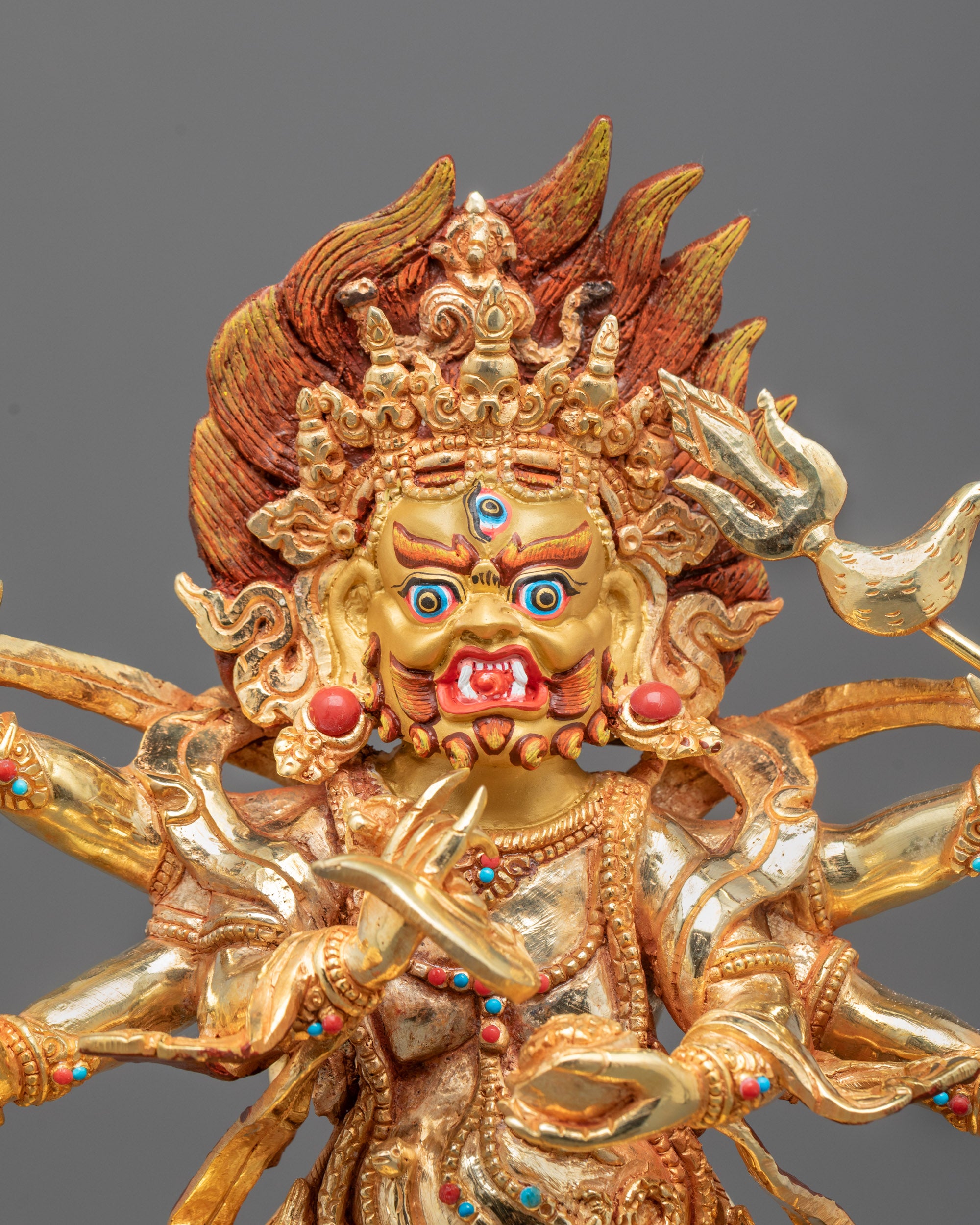 Close-up of wrathful Six Armed Mahakala’s face and detailed gold-plated copper