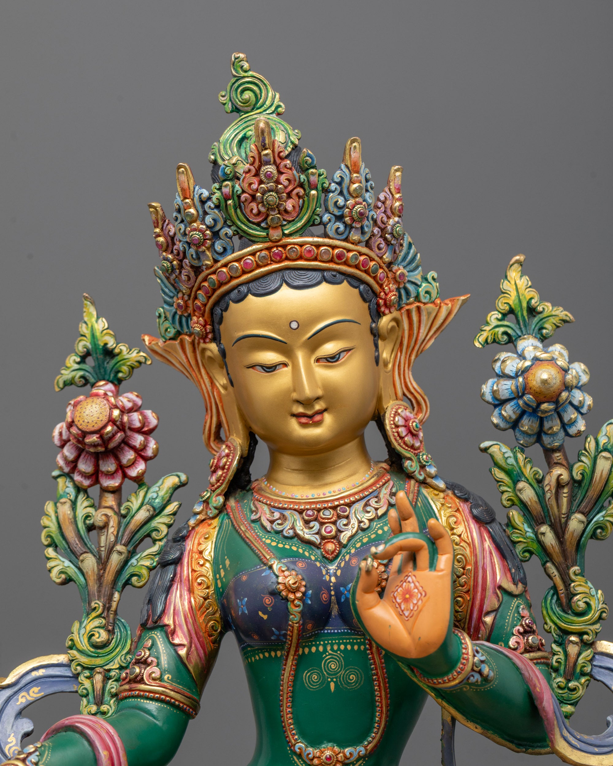 Close-up view of Green Tara statue’s serene face with hand-painted green and gold finish