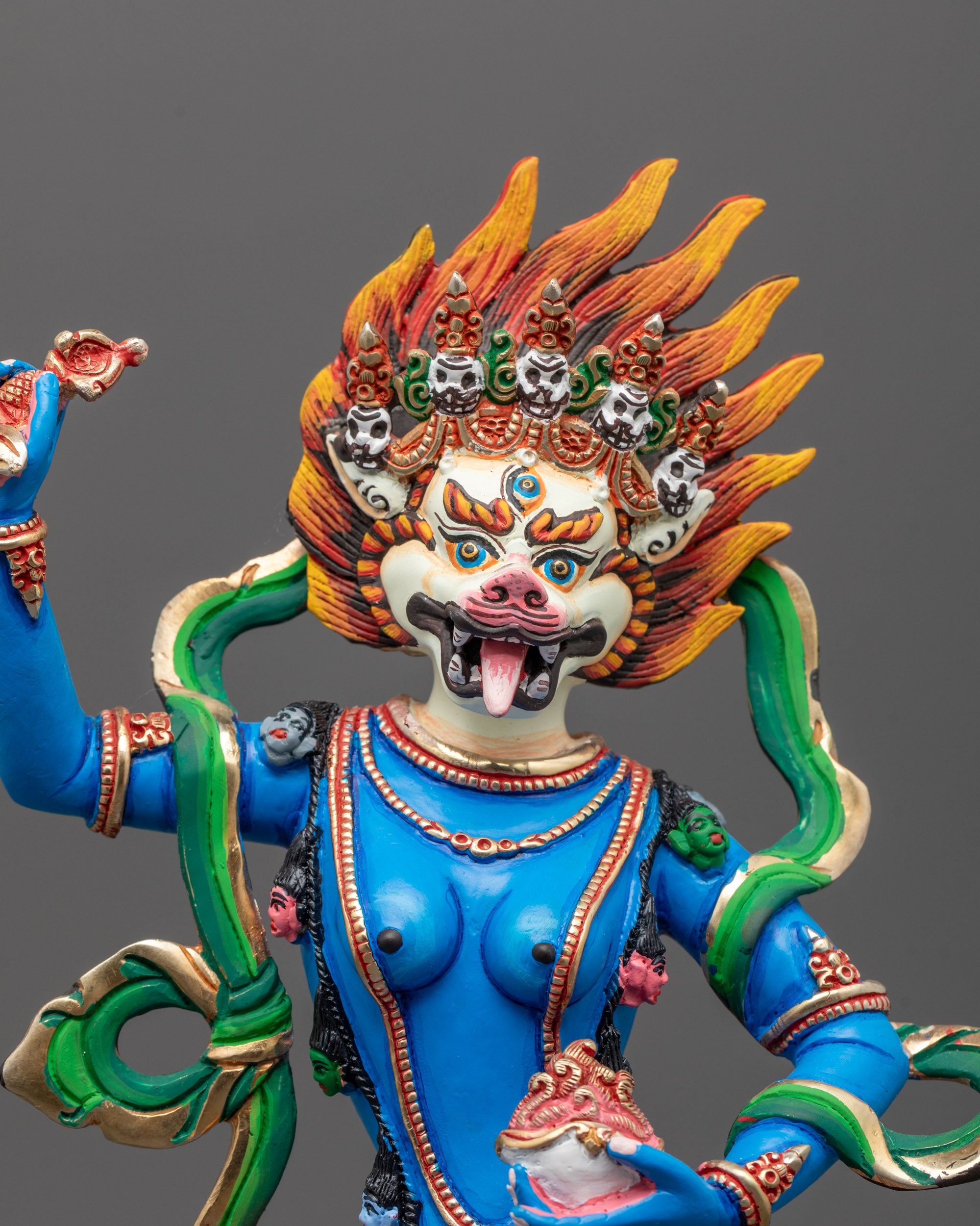 Close-up view of Simha Mukha's lion-faced wrathful expression, painted in vivid blue acrylic
