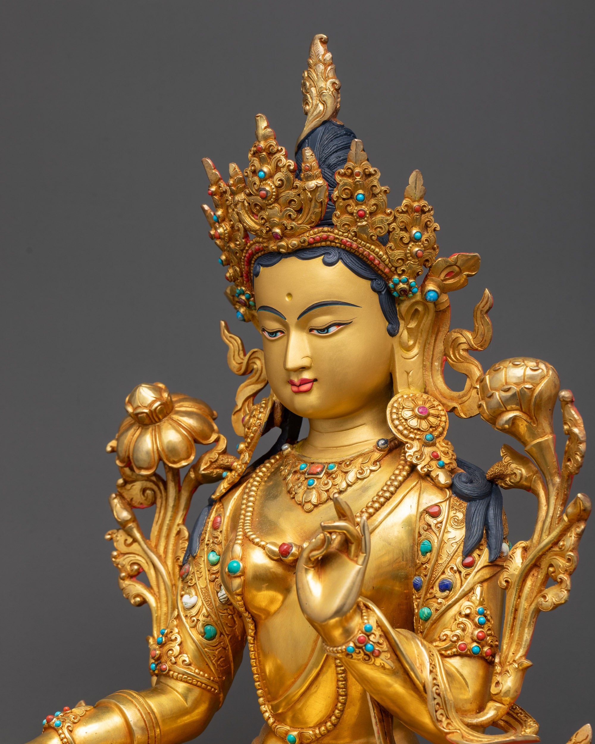 Close side view of Green Tara with intricate armlets and carved lotus seat in royal ease pose