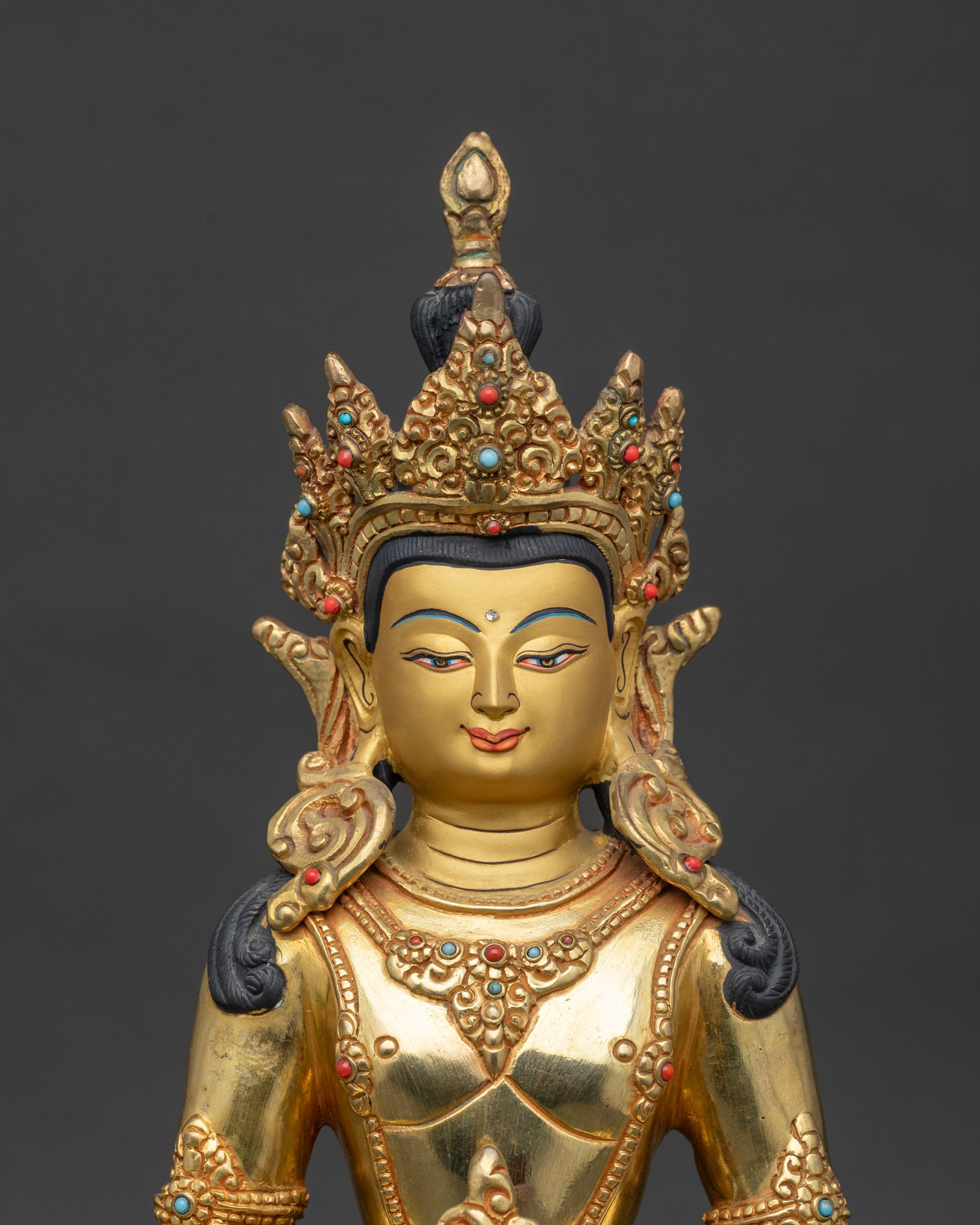 Close up Amitayus Buddha face gold-painted face with five-jewel crown and stones
