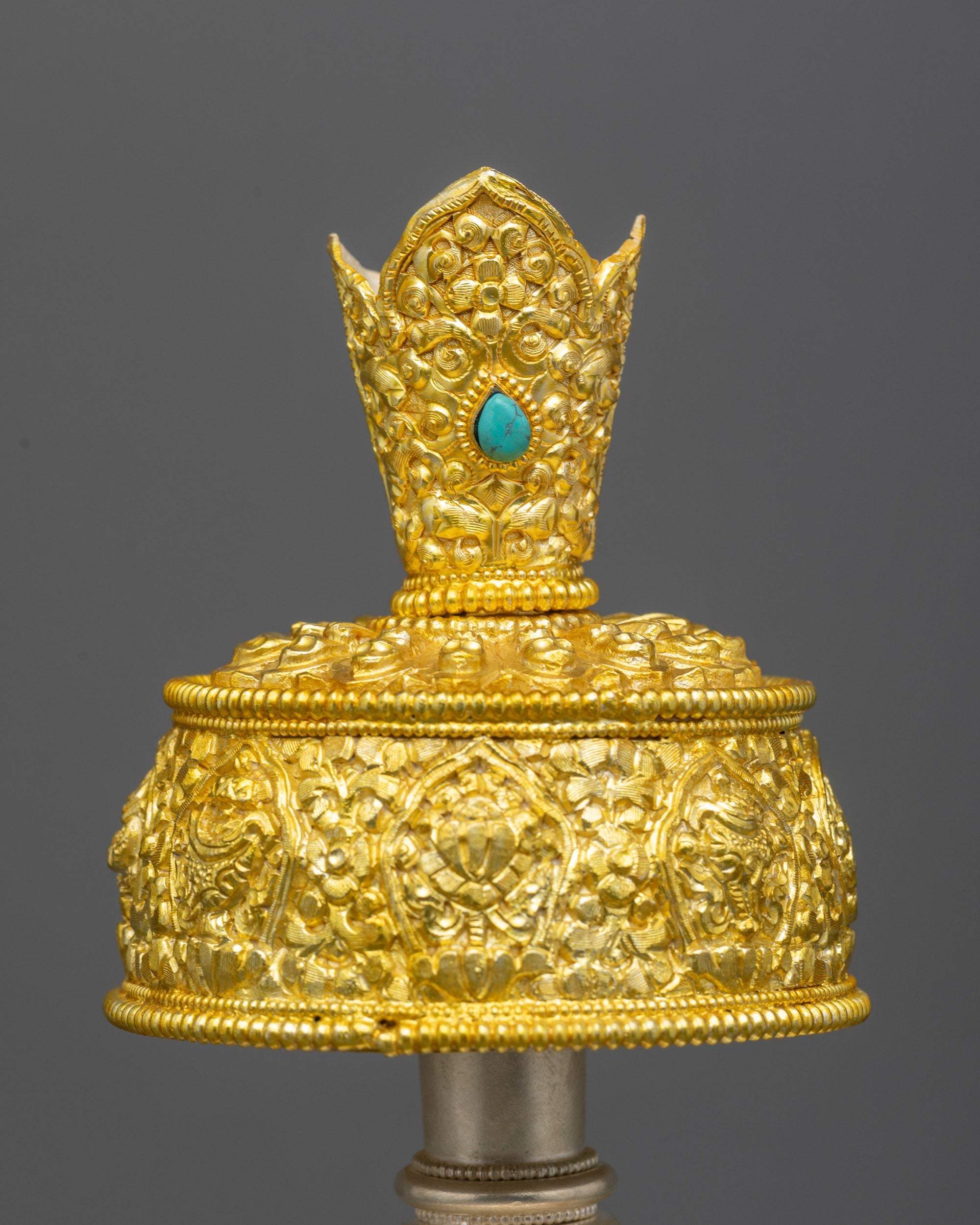 Close up Che Bhumba lid with turquoise gemstones and sacred mantras on finial