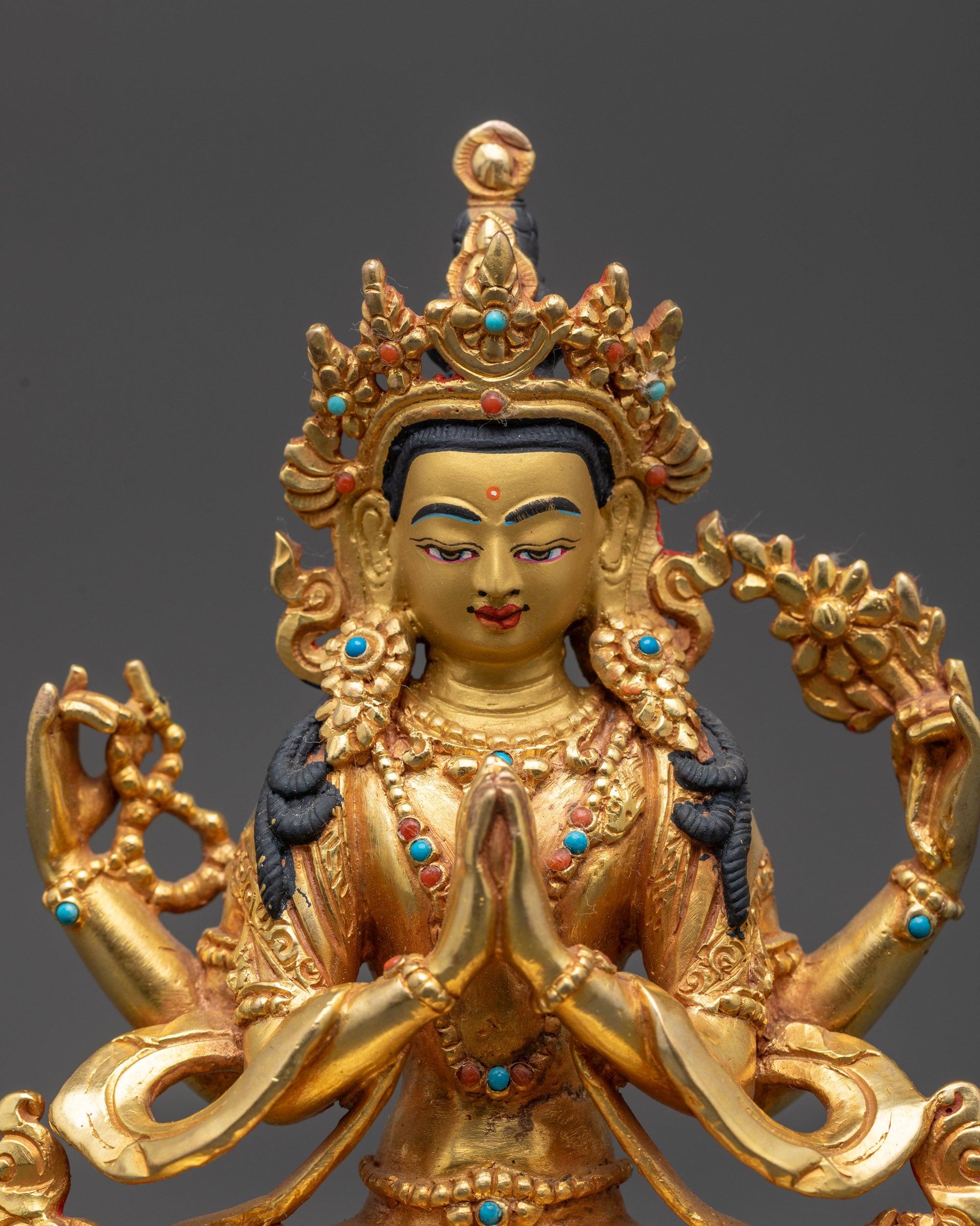 Close up Chenrezig Statue showing serene face, detailed robes, and gold fire-gilding