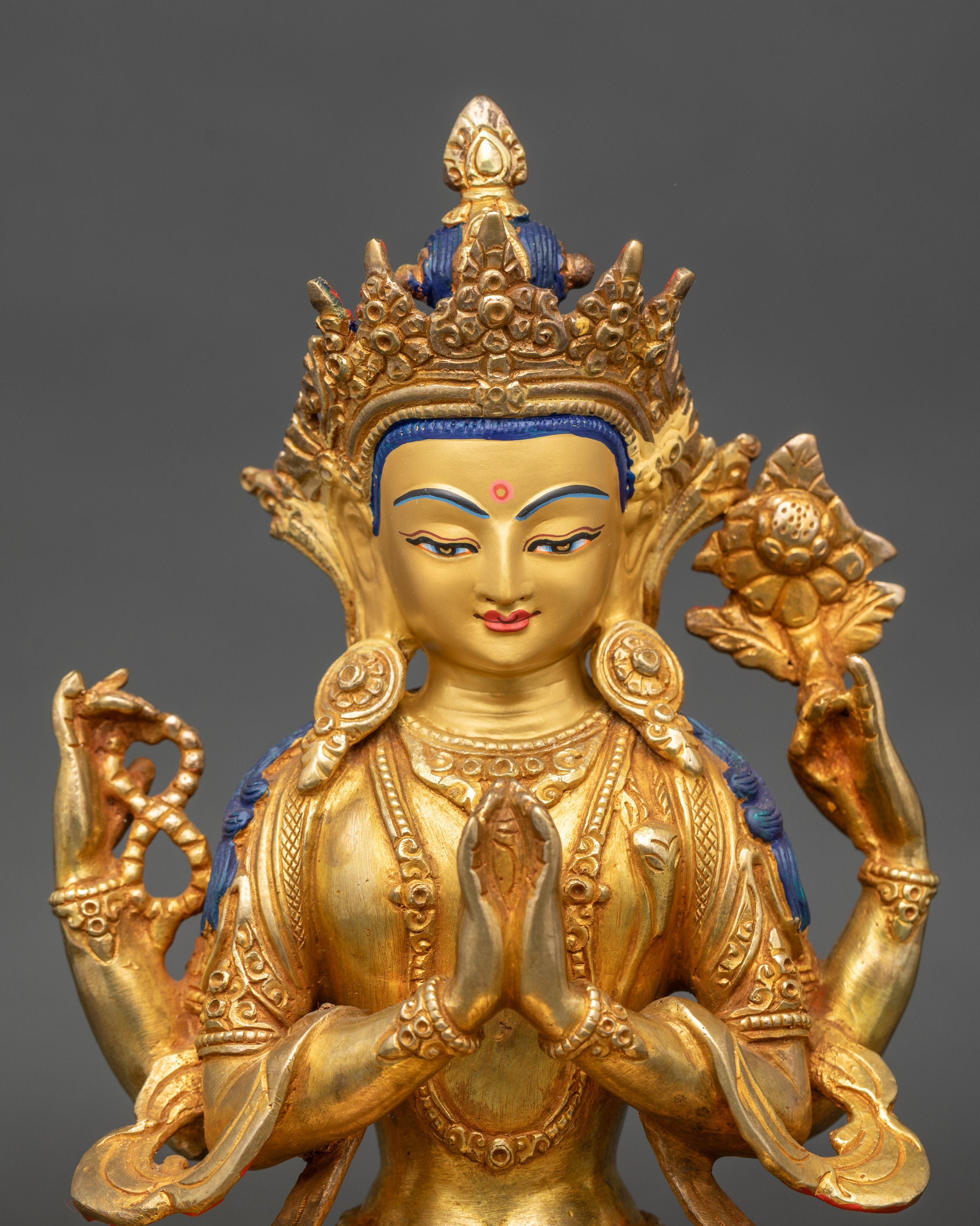 Close up Chenrezig gold-painted face with semi-precious stones and intricate details