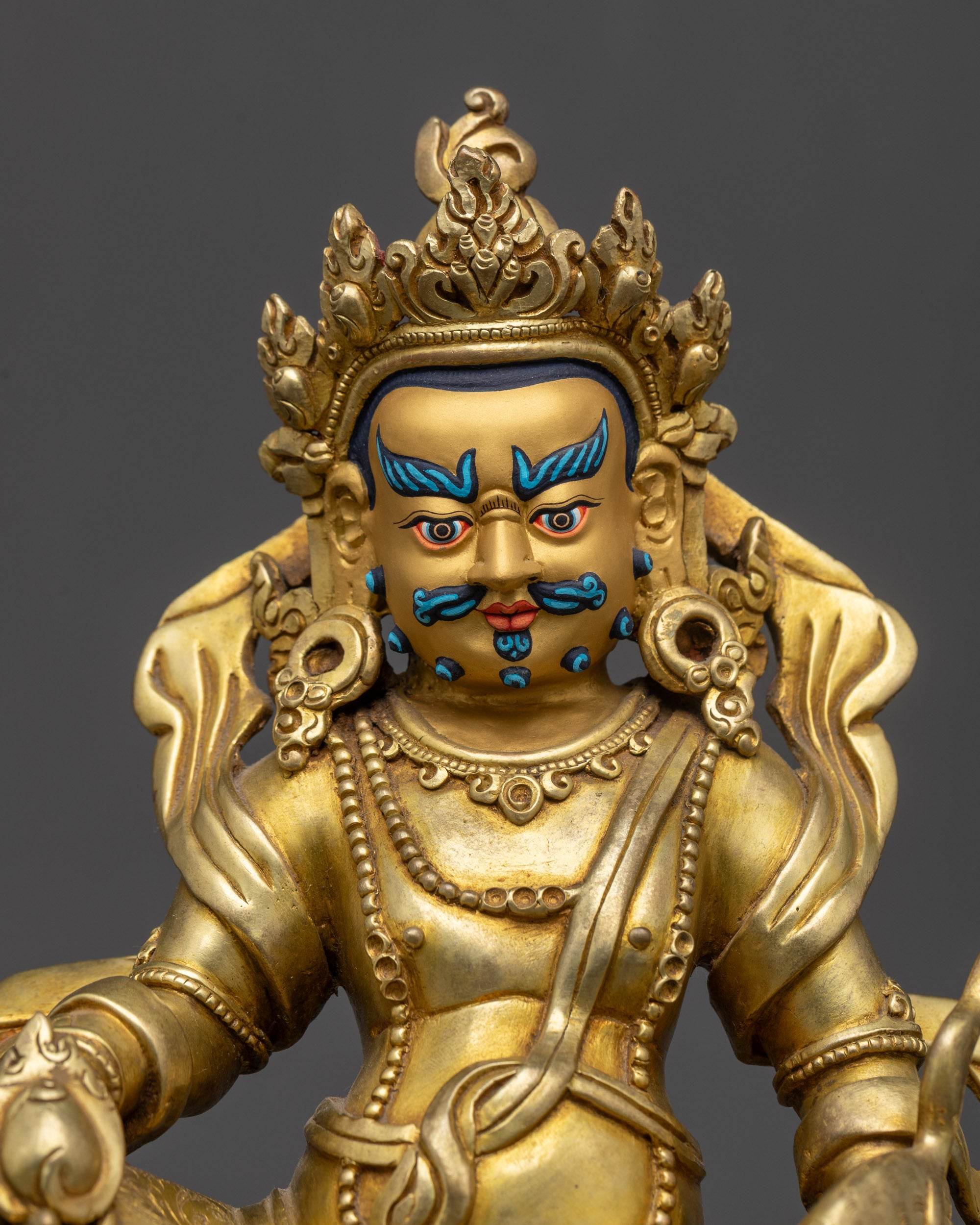 Close up Dzambhala Buddha face showing piercing eyes and vivid blue facial accents
