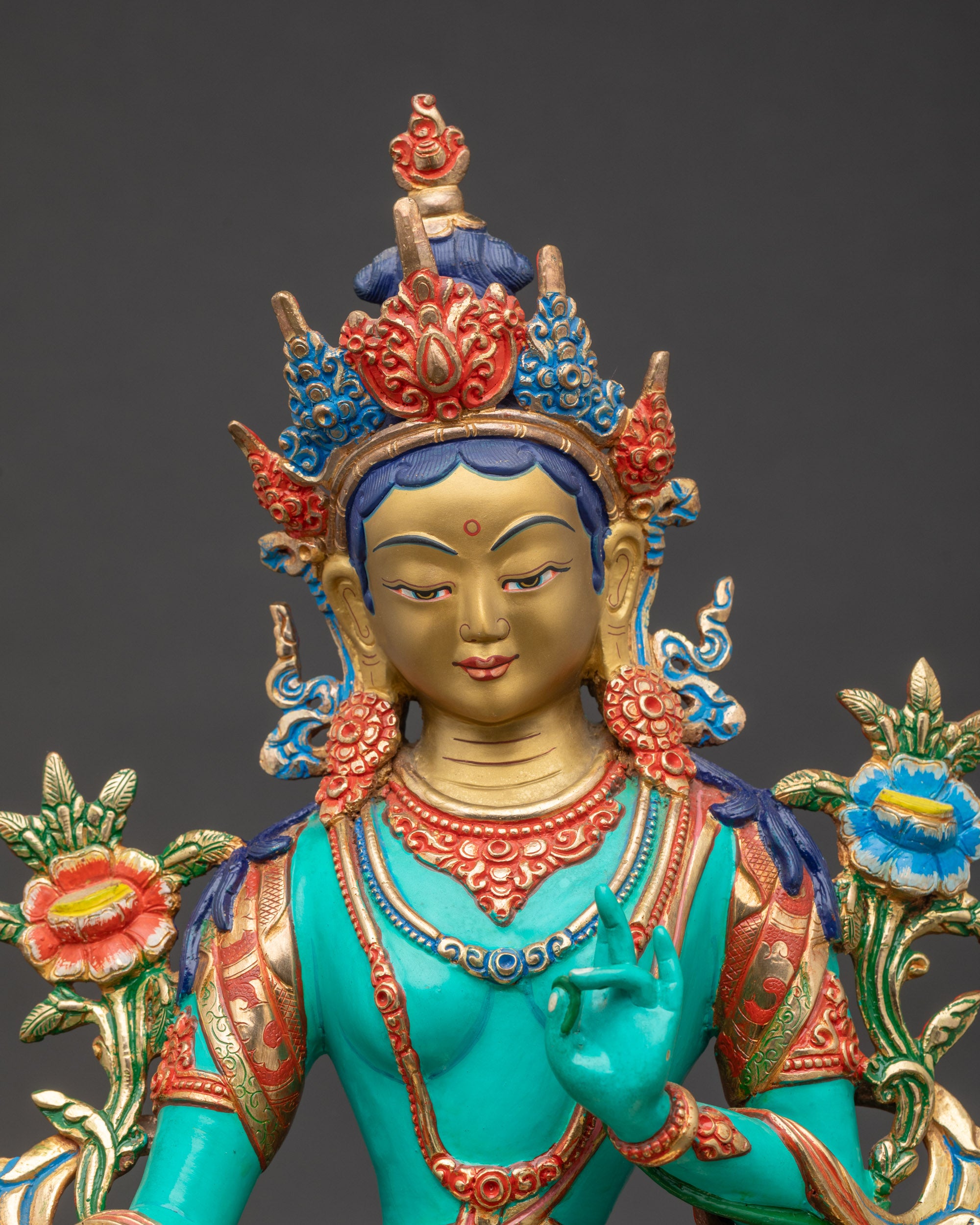 Close up Green Tara face with ornate crown and vibrant gold and jewel-toned details