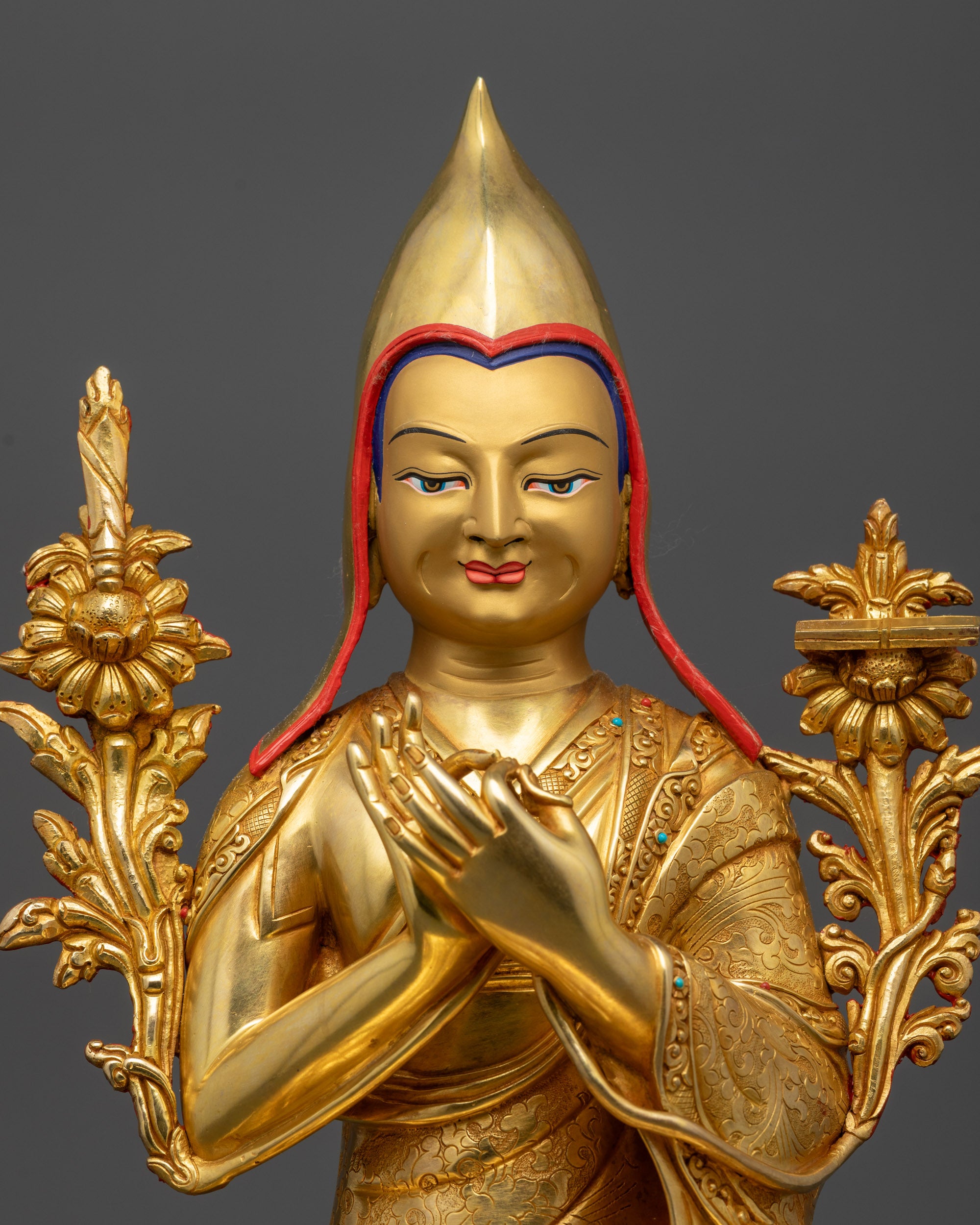 Close up Je Tsongkhapa statue showing Dharmachakra Mudra, utpala flowers, and gold face