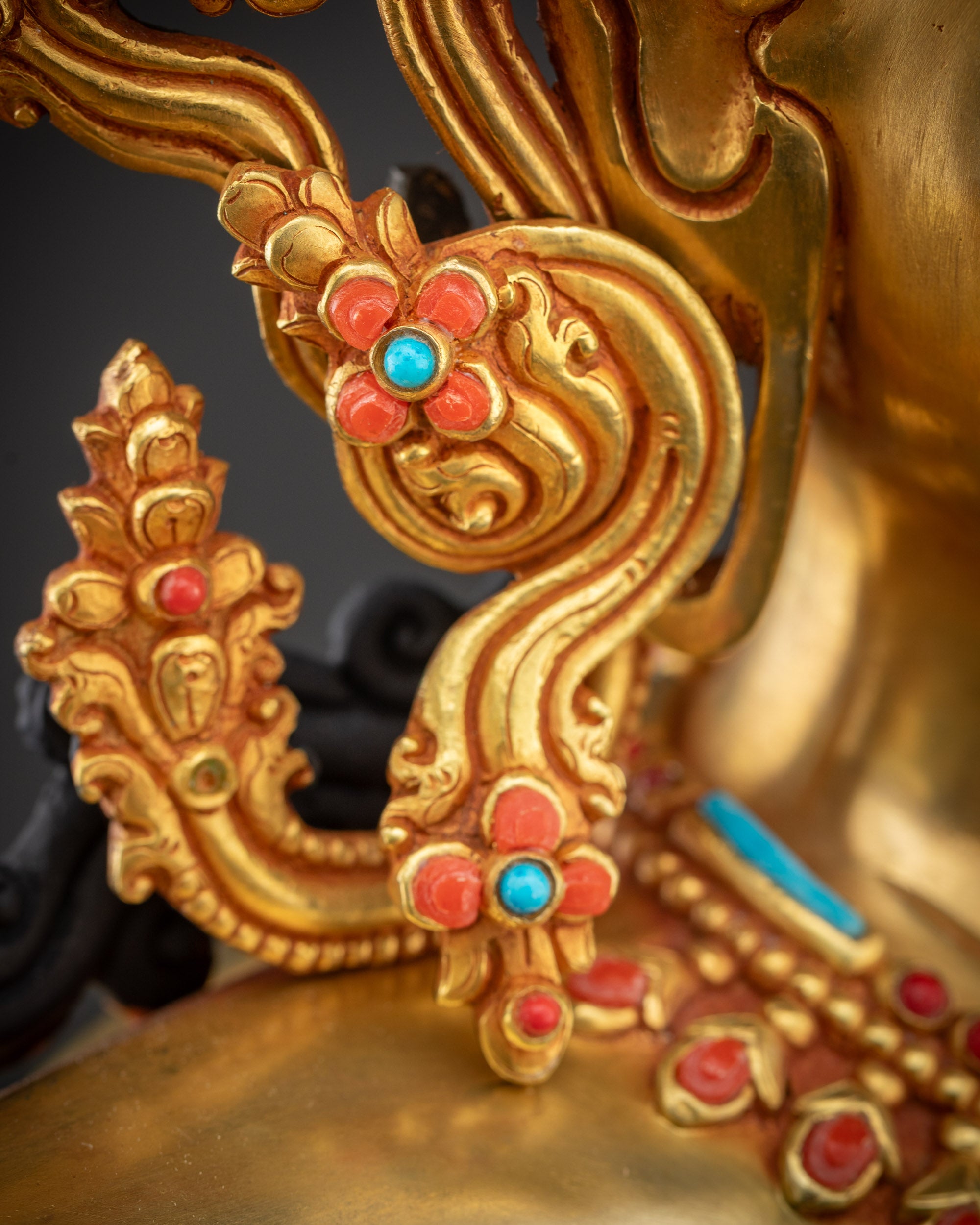 Close up Maha Manjushri Statue right earring detailed gold design with radiant copper highlights