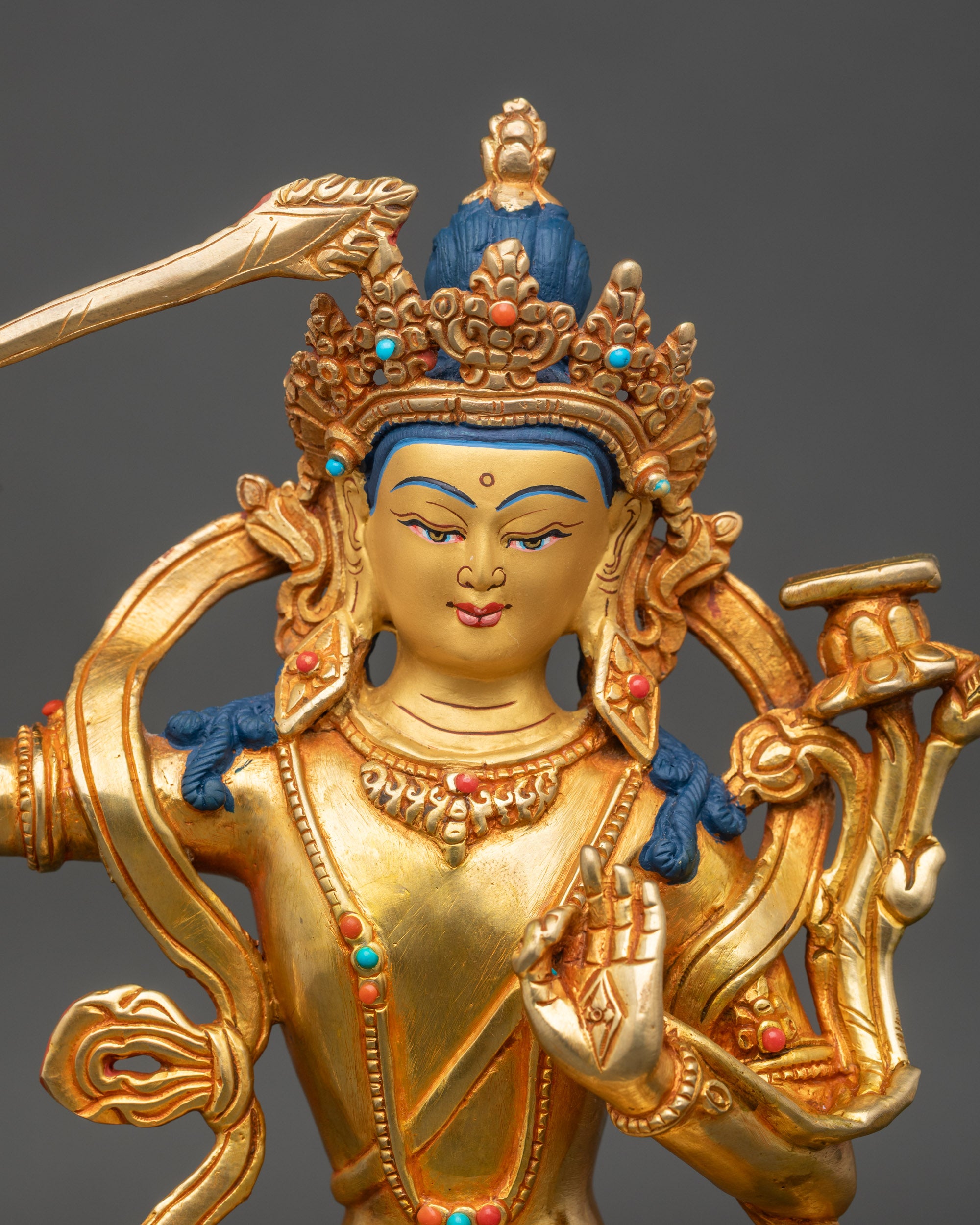 Close up Manjushree face gold-painted copper statue with semi-precious stone inlay