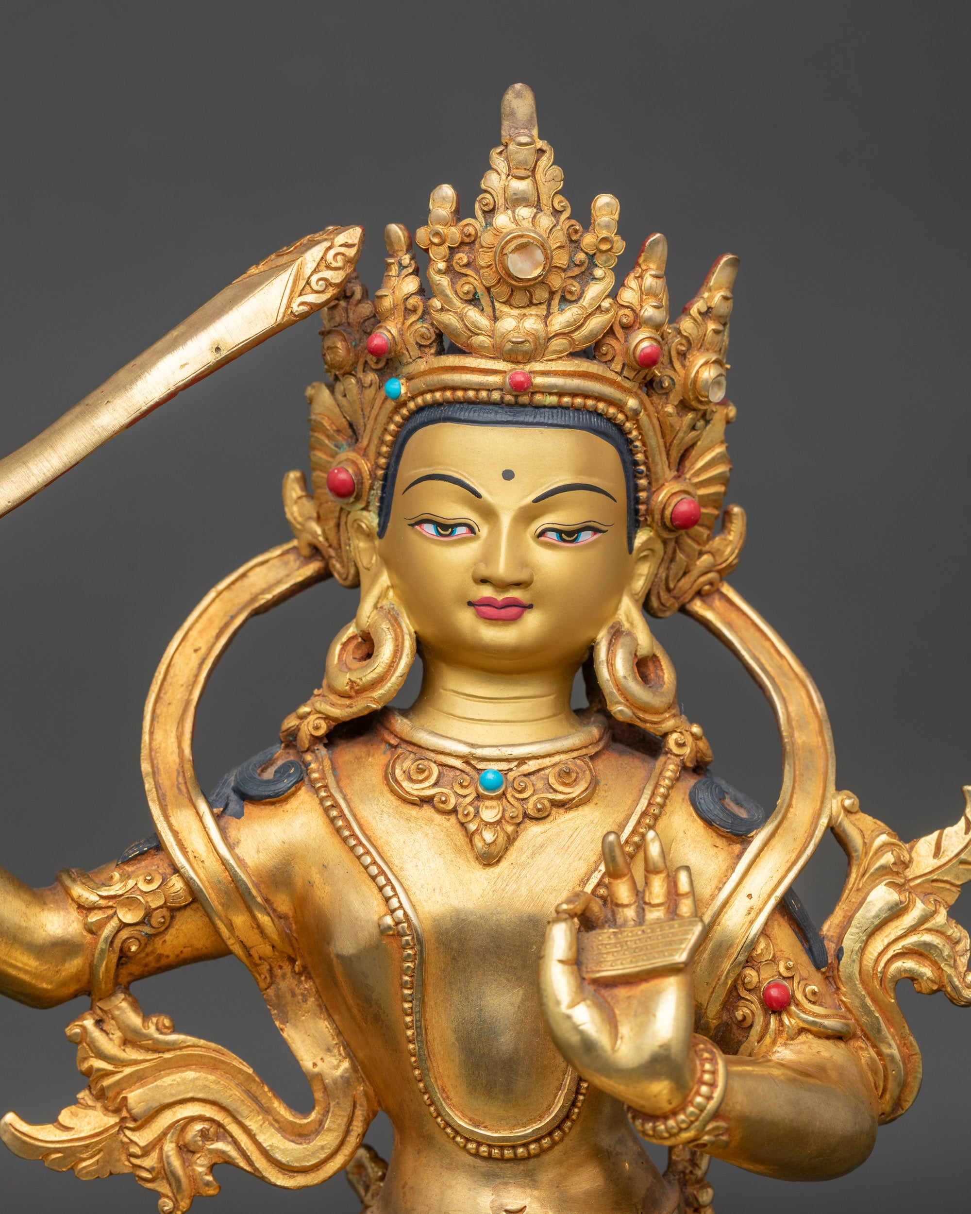 Close up Manjushree gold-painted face with coral stones, Himalayan wisdom bodhisattva