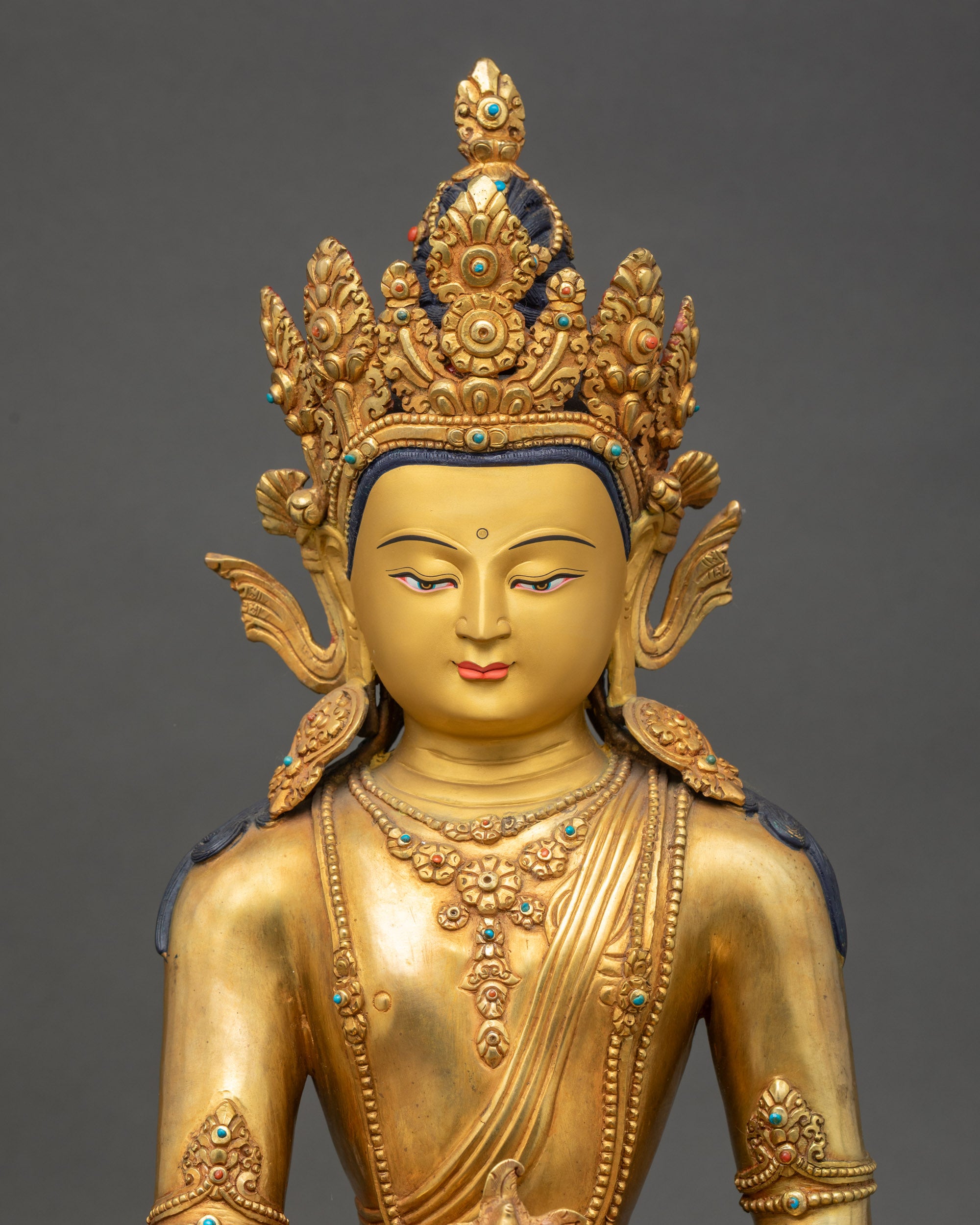 Close up Medicine Buddha gold-painted face with crown, turquoise coral inlay