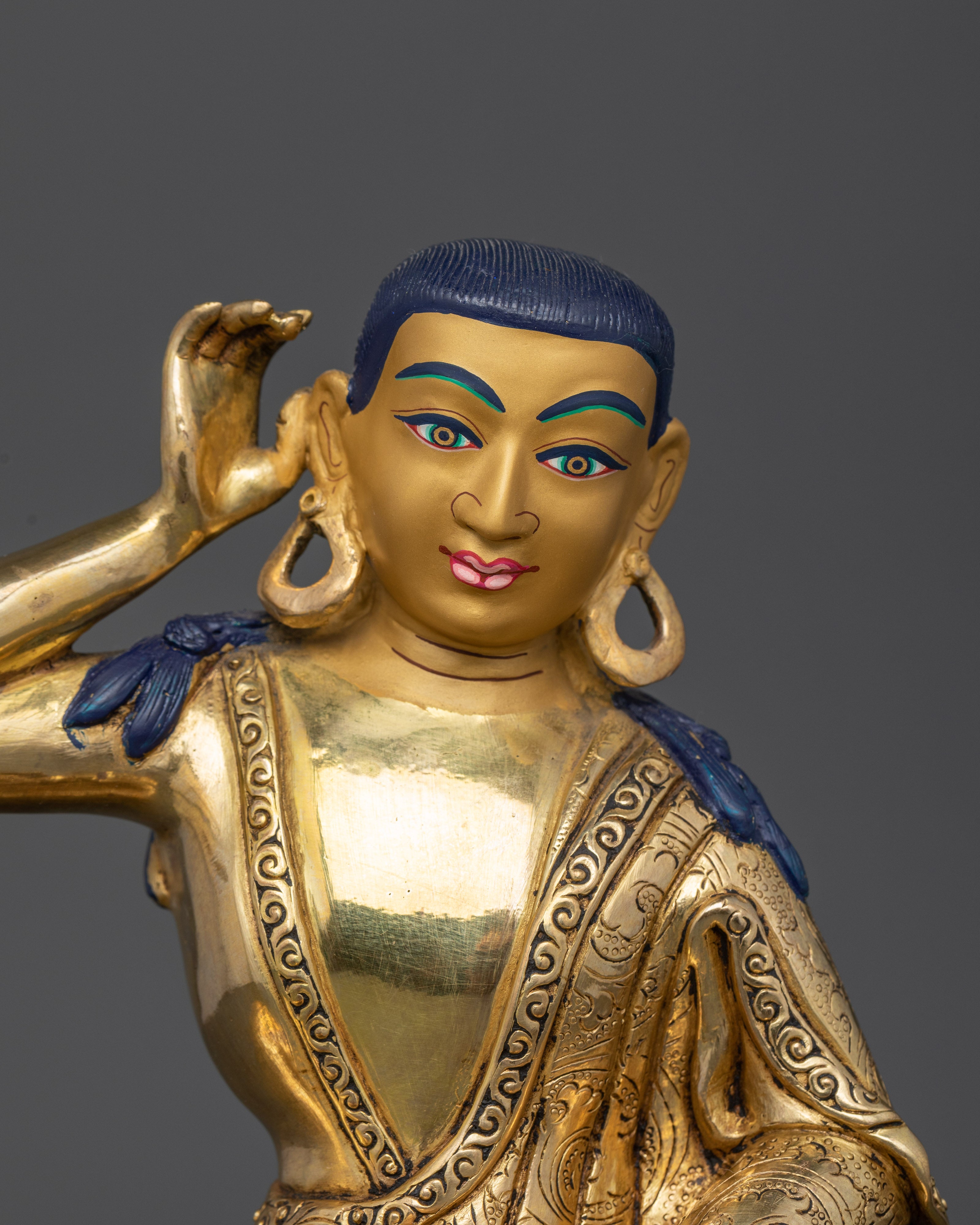 Close up Milarepa gold-painted face listening pose detailed robe carving