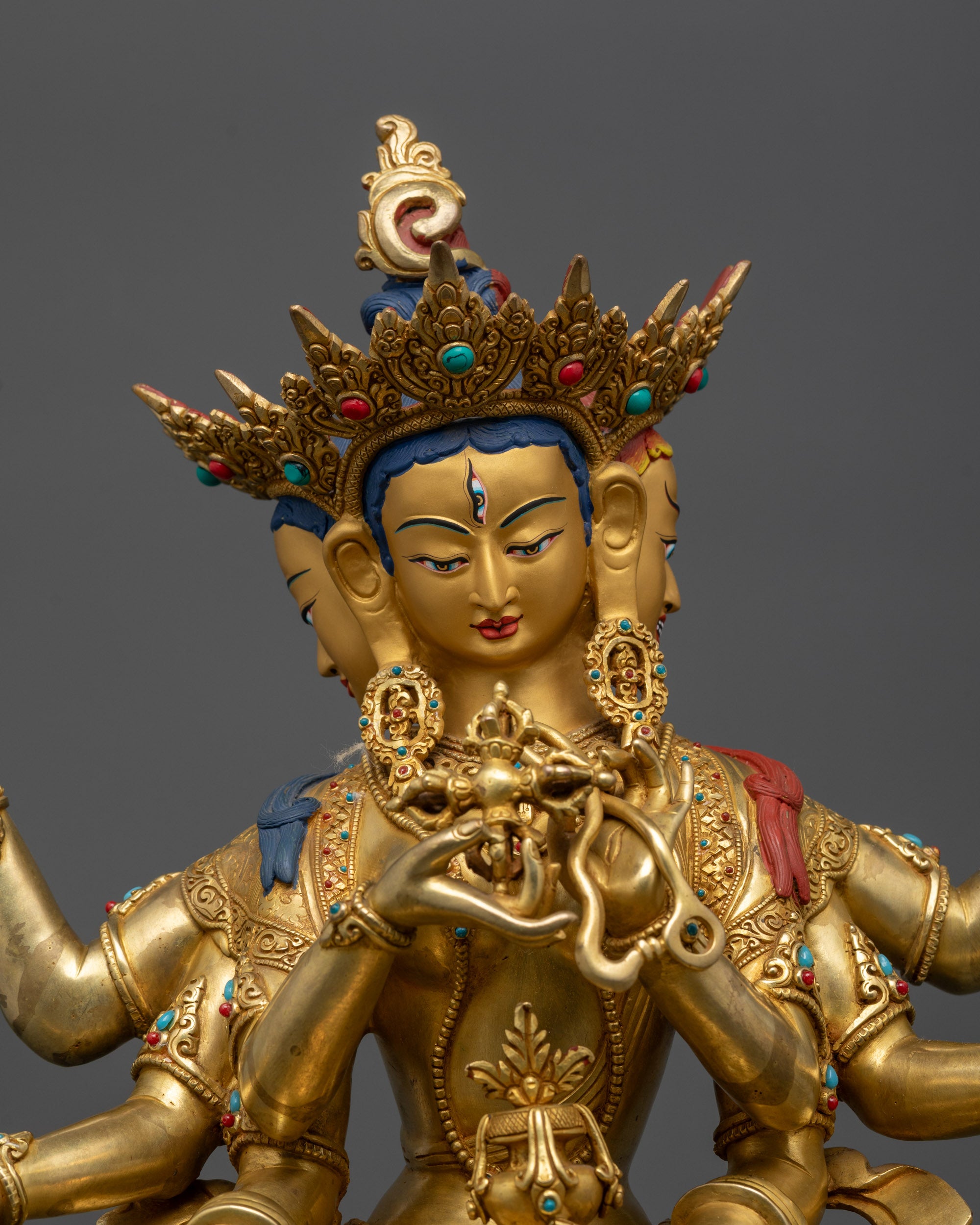 Close up Namgyalma statue showing three gold-gilded faces and sacred objects details