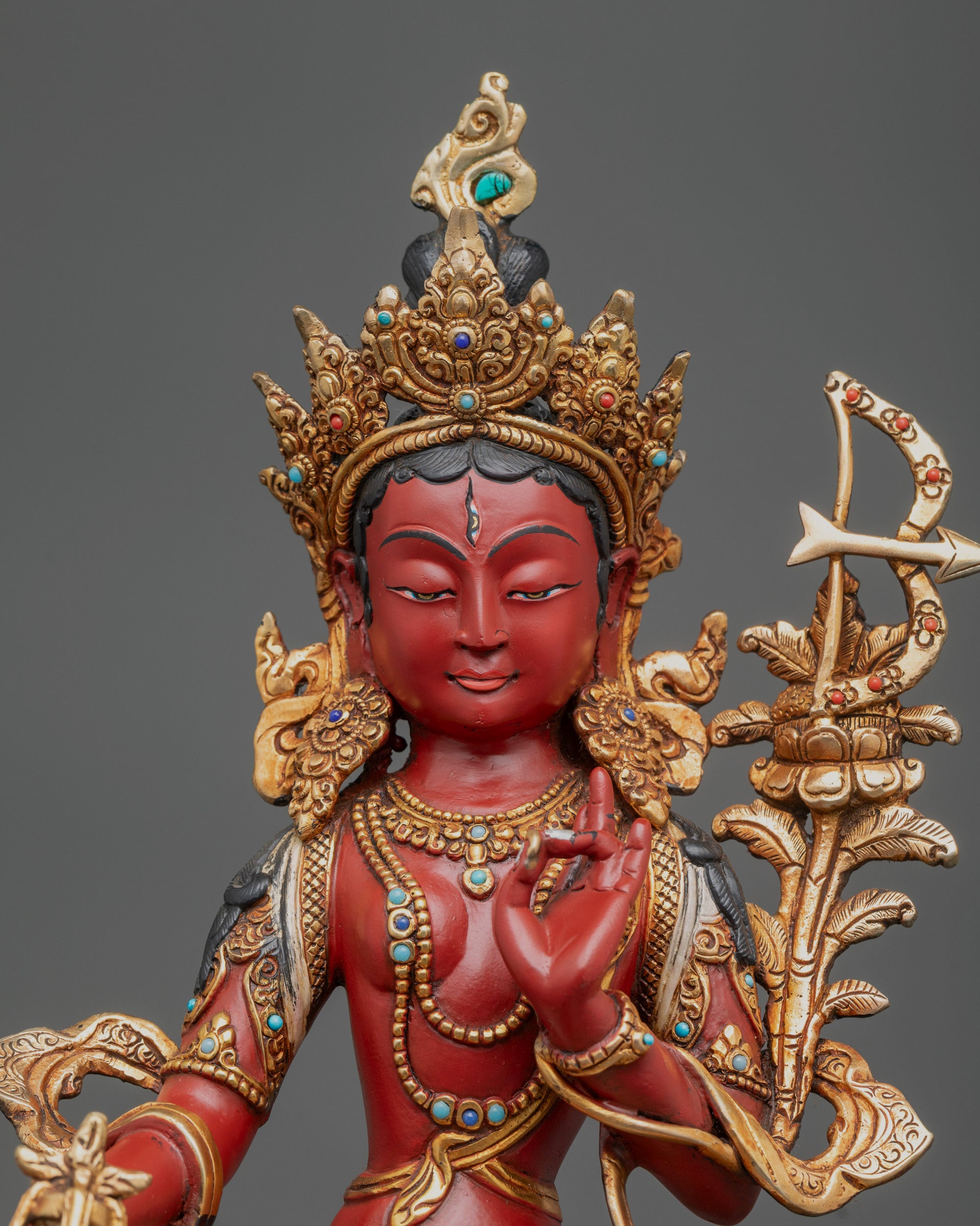Close up Red Tara Statue showing serene face, third eye, crown, and intricate carvings