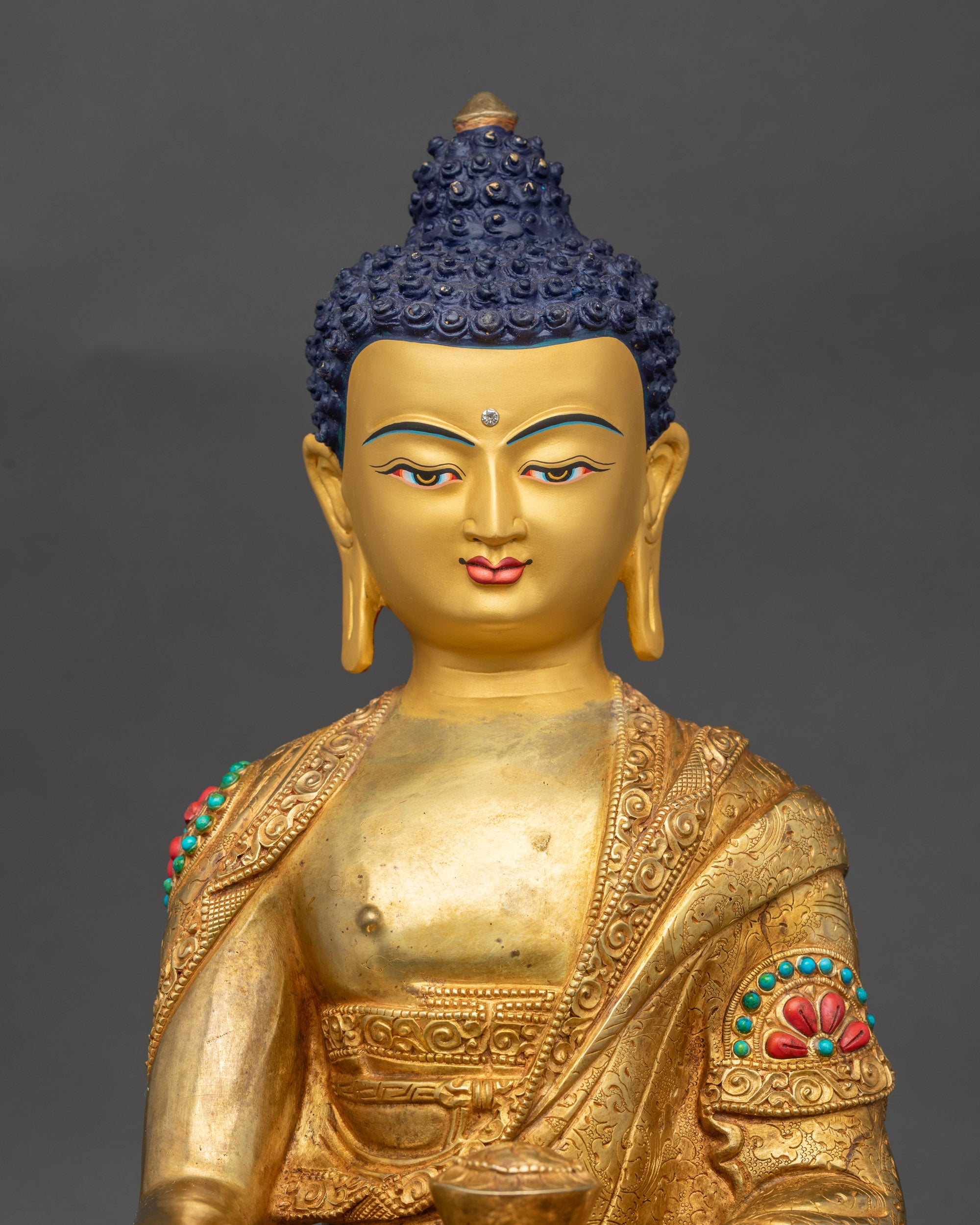 Close up Shakyamuni Buddha face gold-painted halo semi-precious stones detail