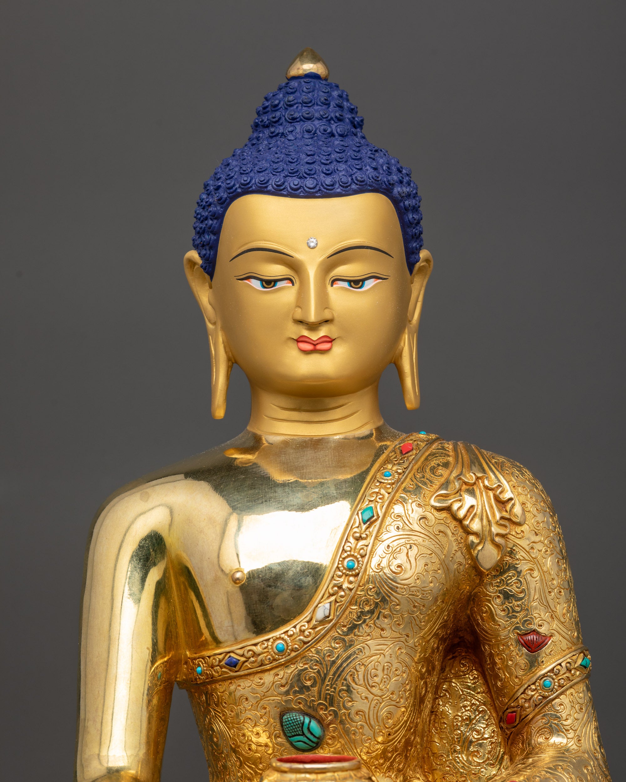Close up Shakyamuni Buddha face showing gold fire-gilded features and semi-precious stones