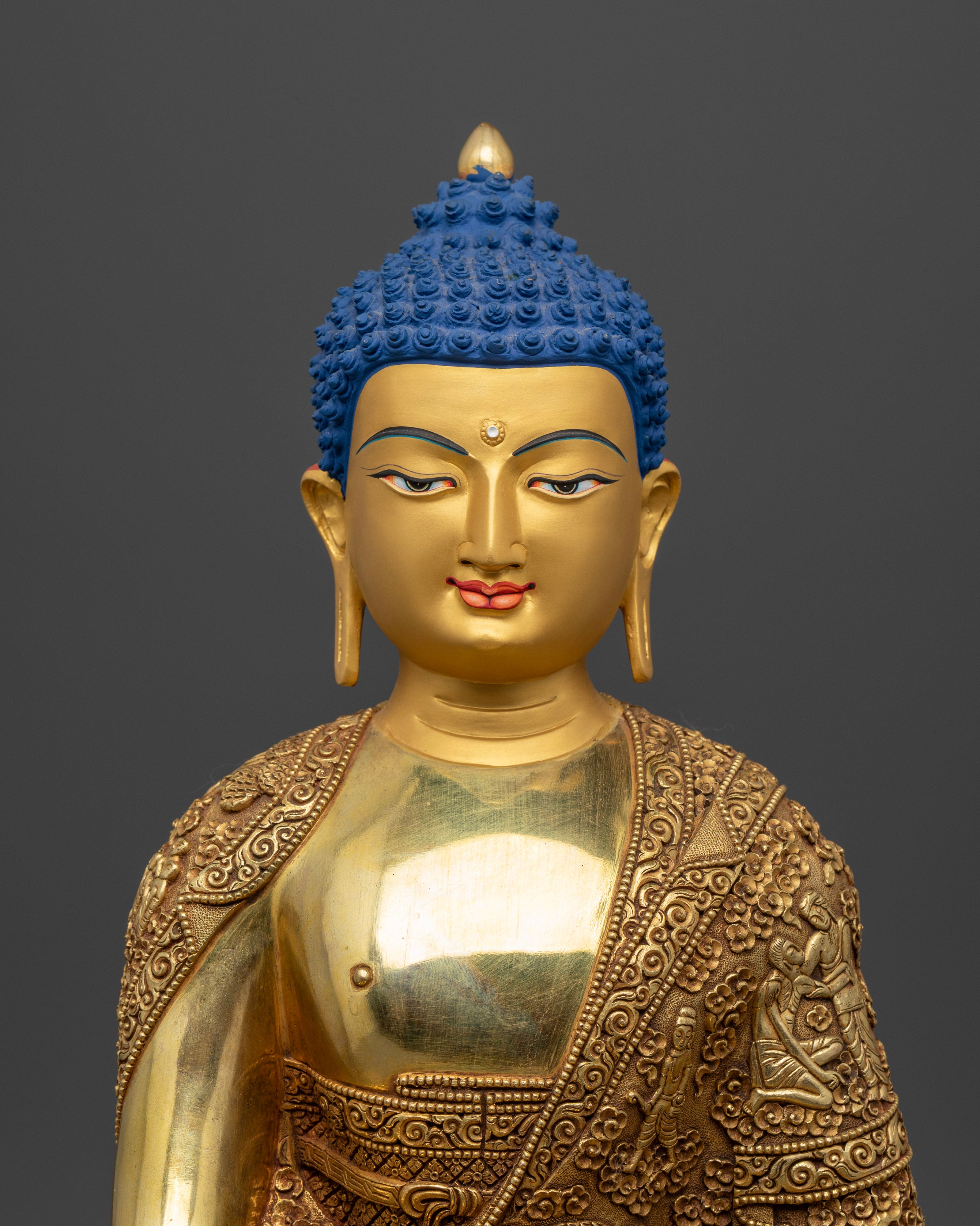 Close up Shakyamuni Buddha statue gold-painted face engraved robe Himalayan artisan art