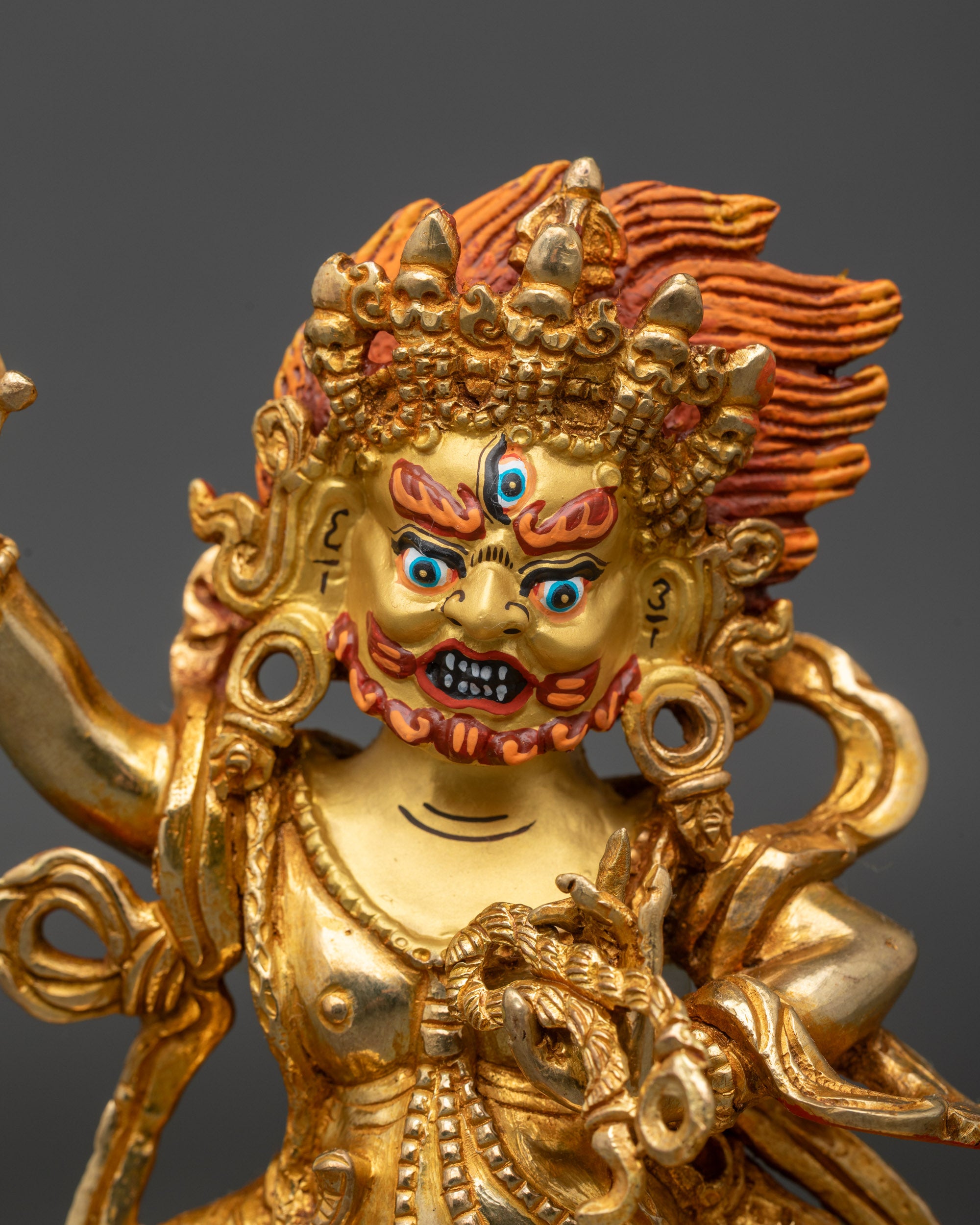 Close up Vajrapani Chana Dorje statue gold-painted face wrathful deity detail