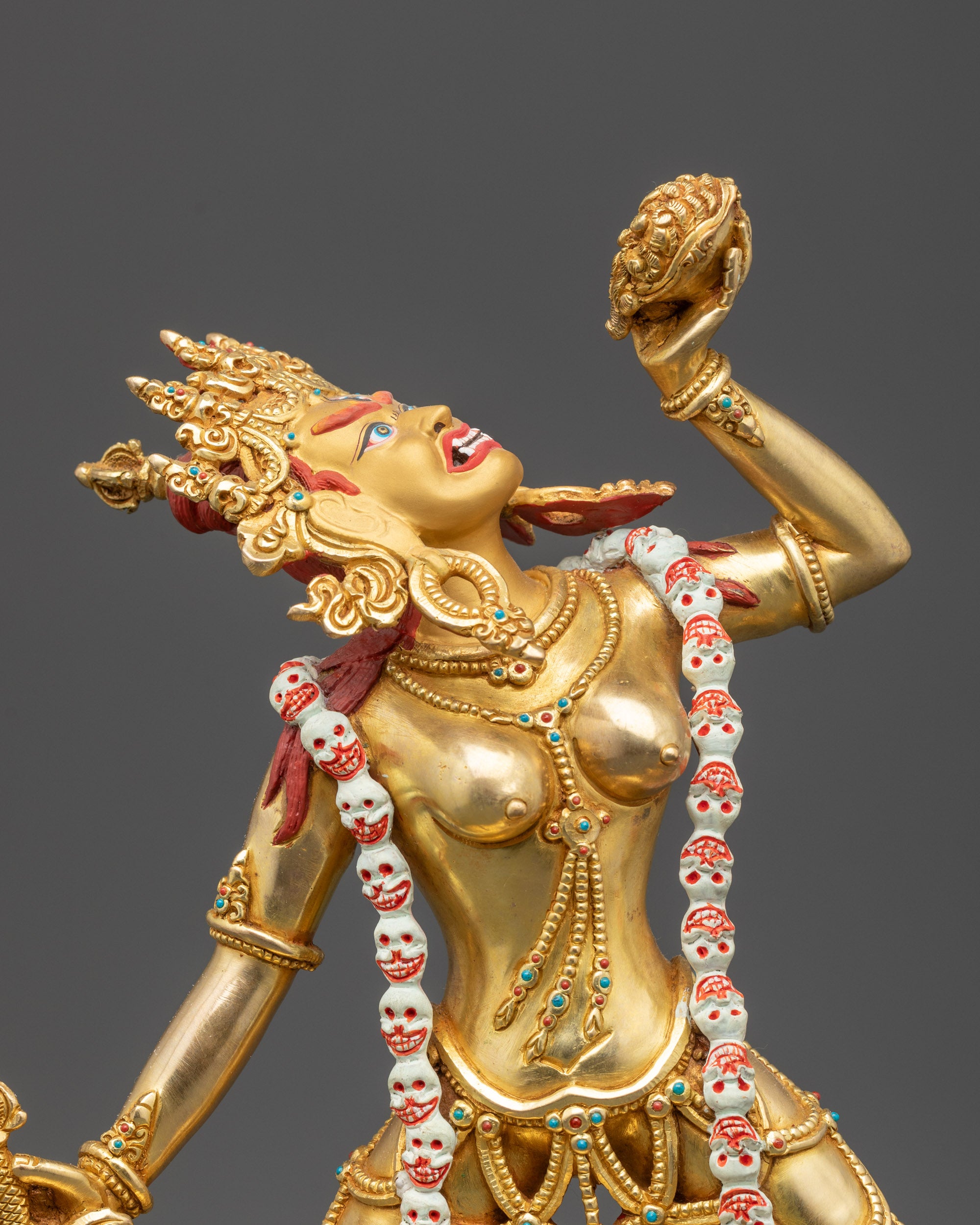 Close up Vajrayogini statue showing wrathful expression, third eye, and skull garland in detail