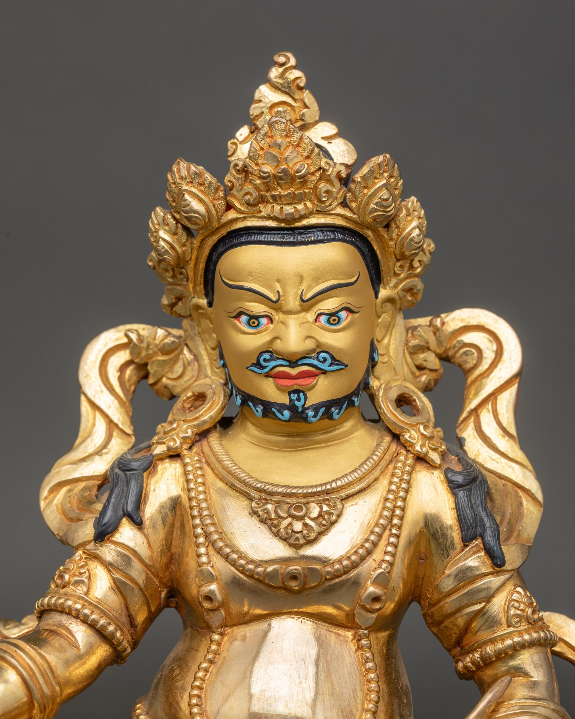 Close up Yellow Dzambhala gold-painted face with opulent jewelry, handmade Newari art