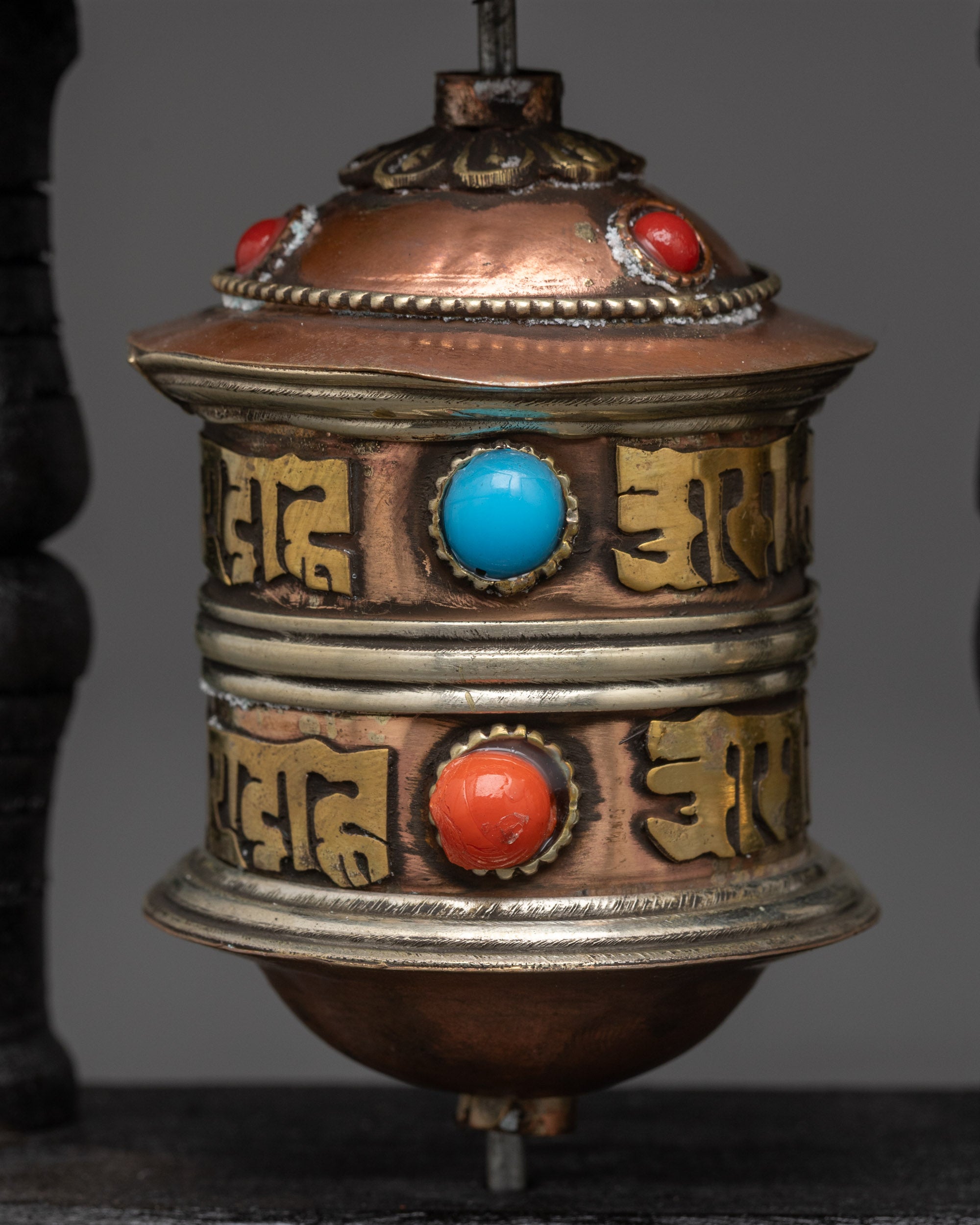 Close up copper and brass prayer wheel with Om Mani Padme Hum mantra and turquoise stones