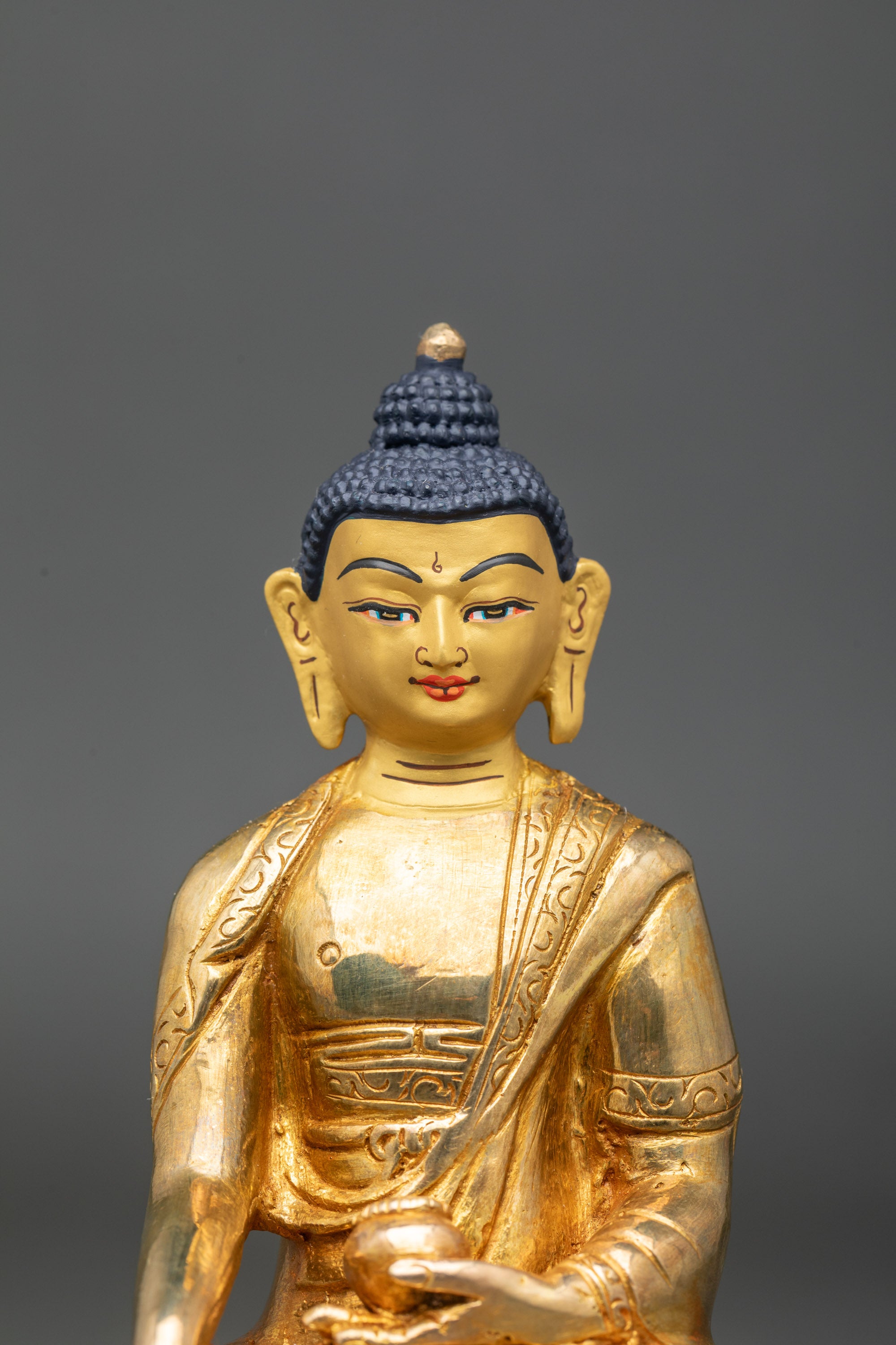 Close up gold-painted face Buddha Shakyamuni handcrafted Nepalese sculpture