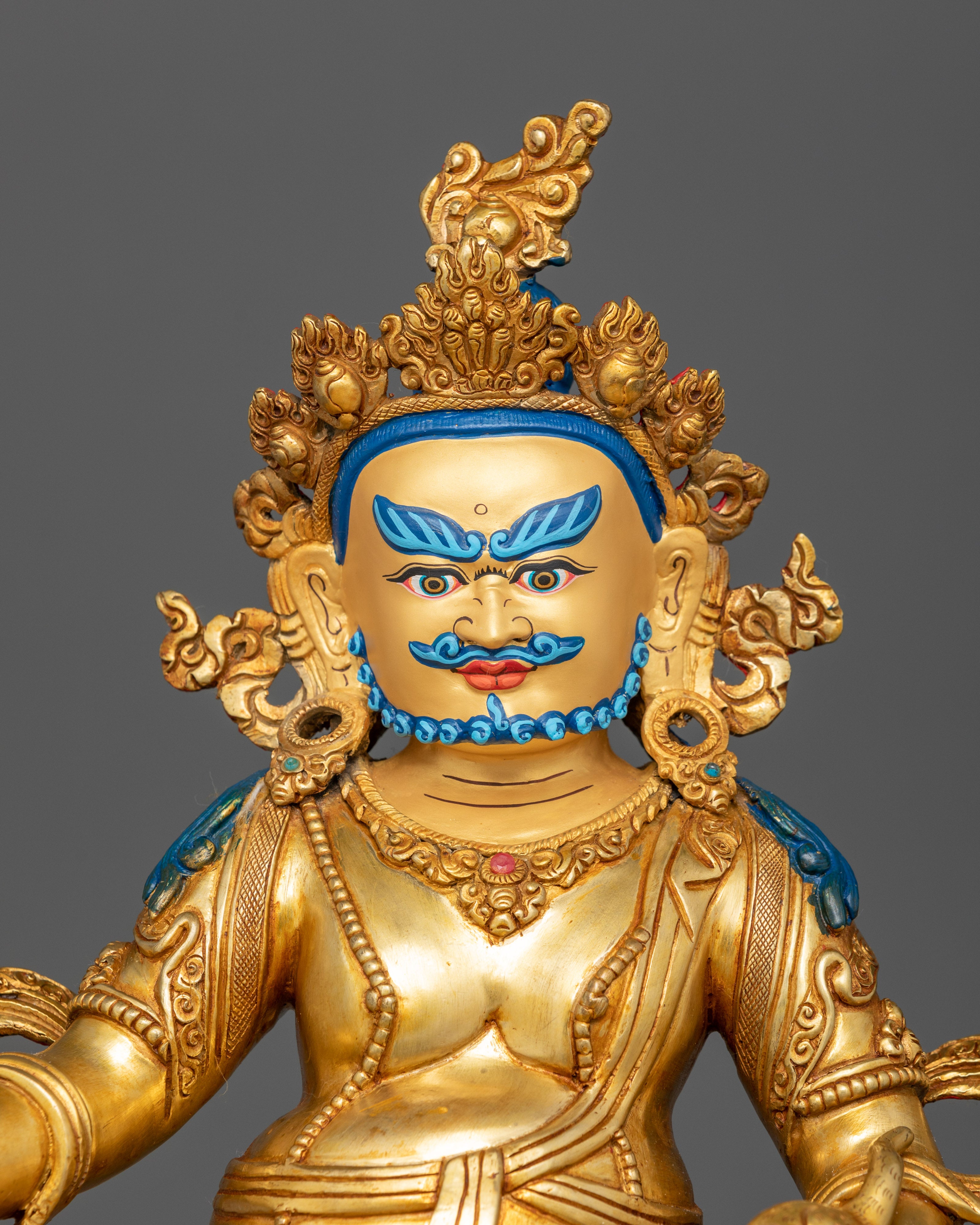 Close up gold-painted face Yellow Dzambhala Buddhist prosperity deity