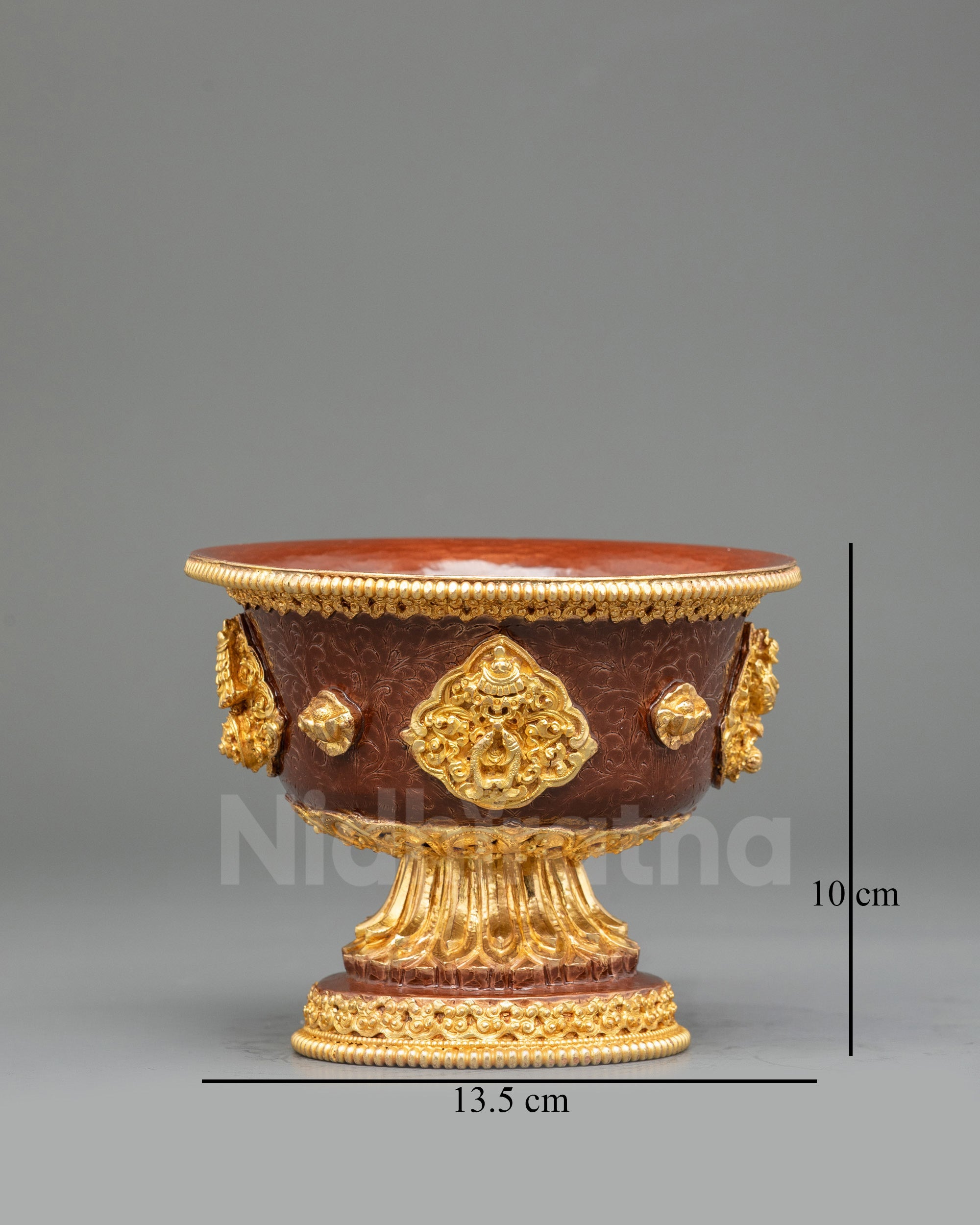 Close up gold-plated Tibetan water offering bowl with smooth pedestal and hand-painted details