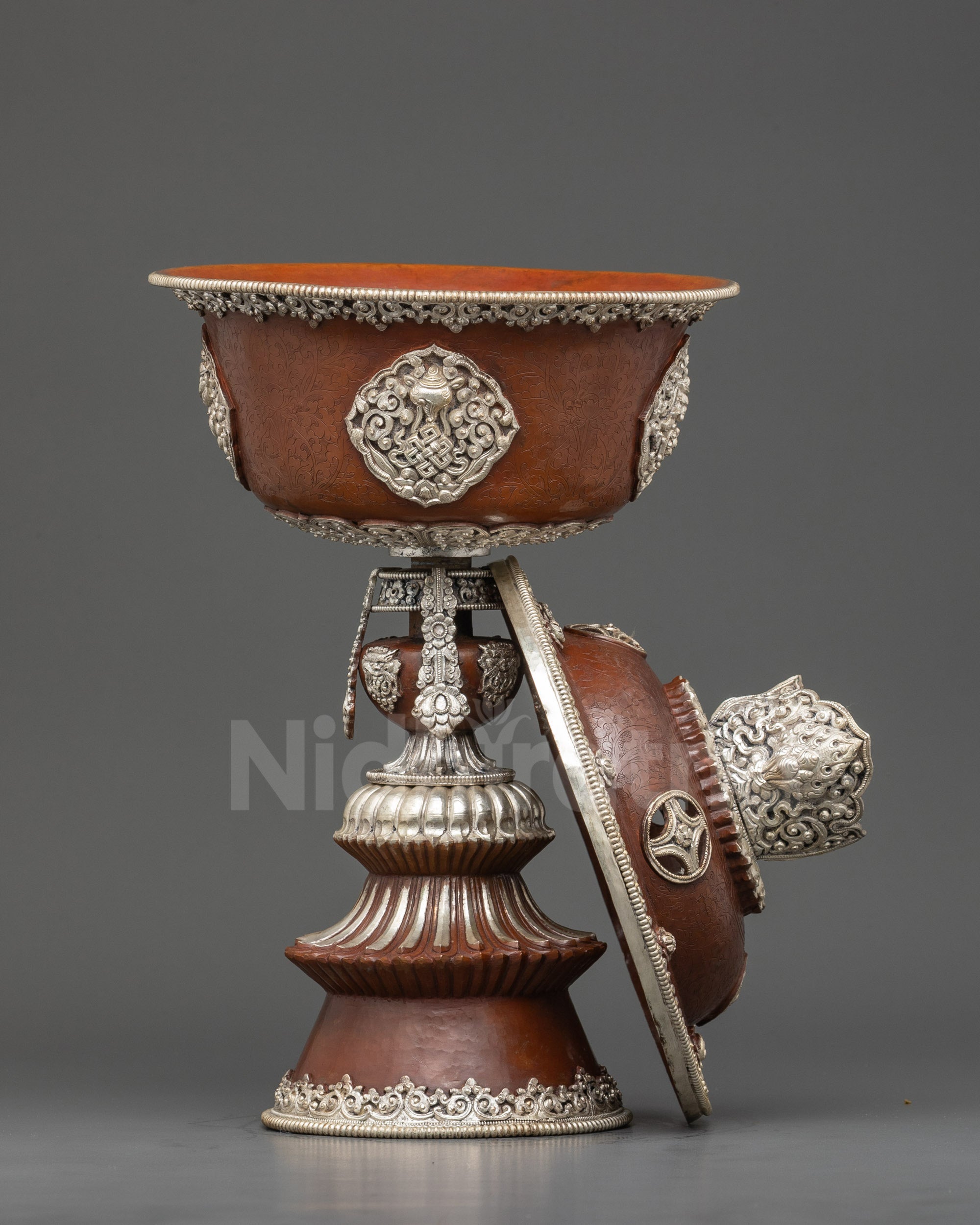 Close up handmade Newari artisan butter lamp with carved auspicious symbols and oxidized finish