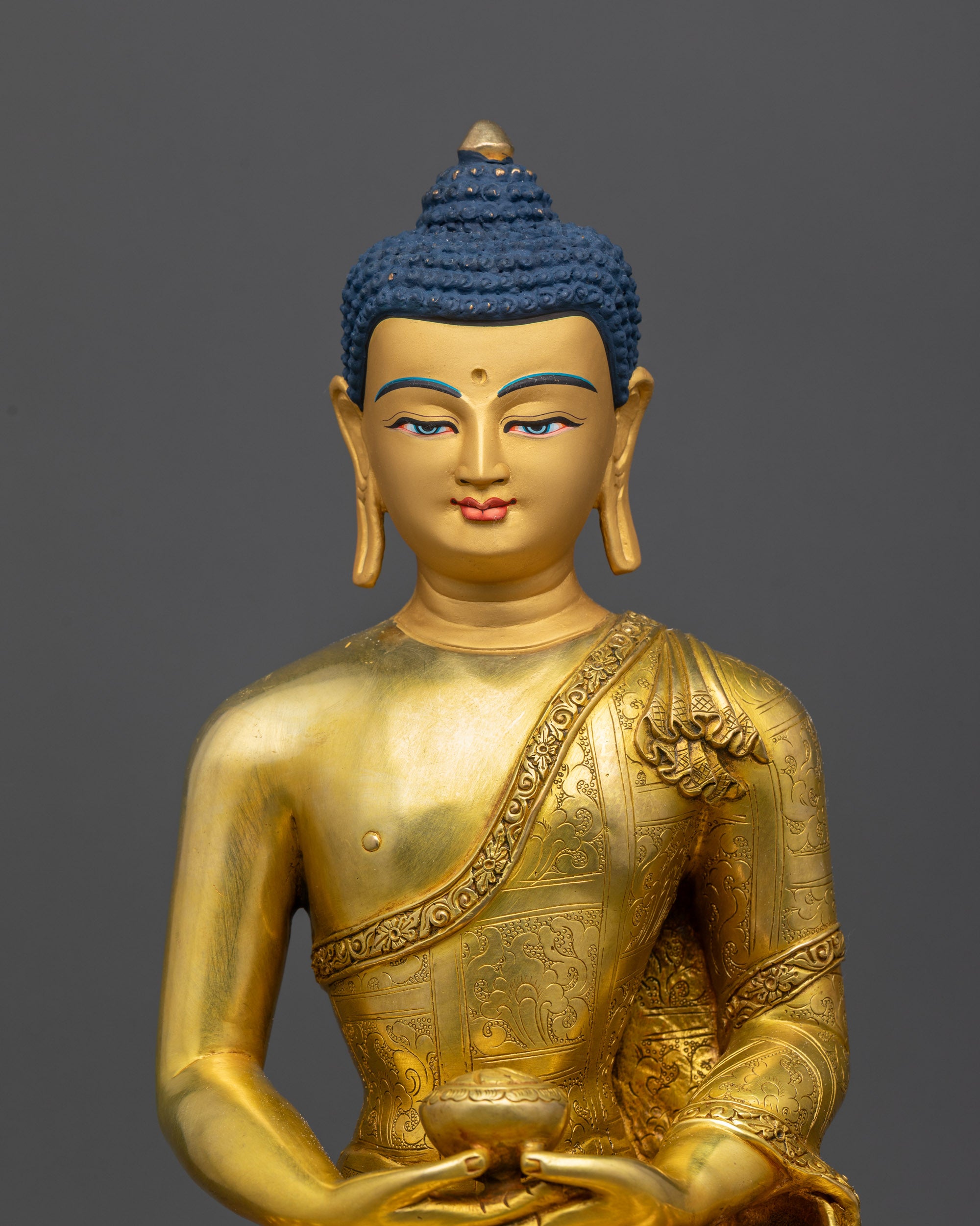 Close up of Amitabha Buddha Statue face with calm expression and gold-gilded finish