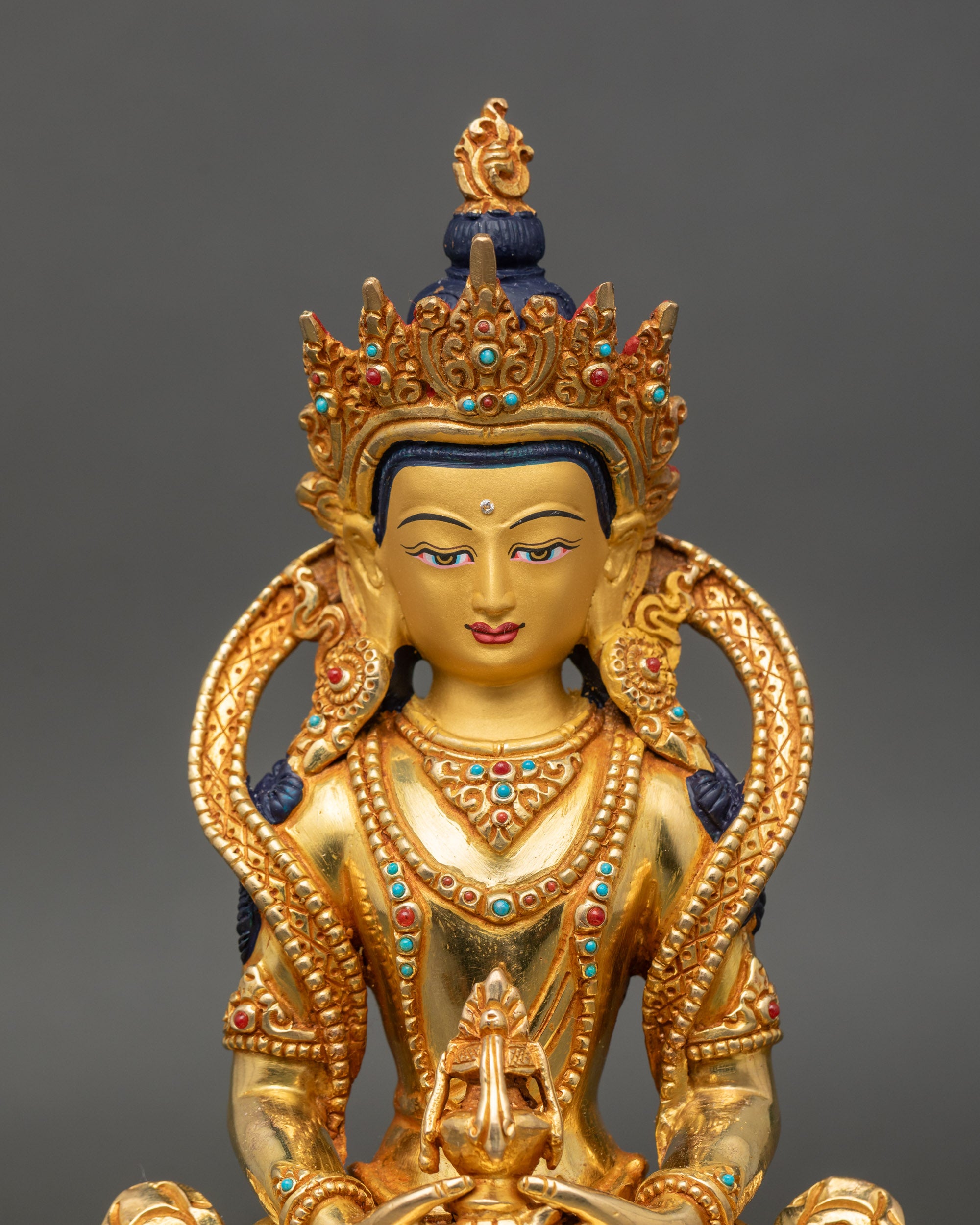 Close up of Amitayus Buddhaβs serene face with gold detailing and semi-precious stones