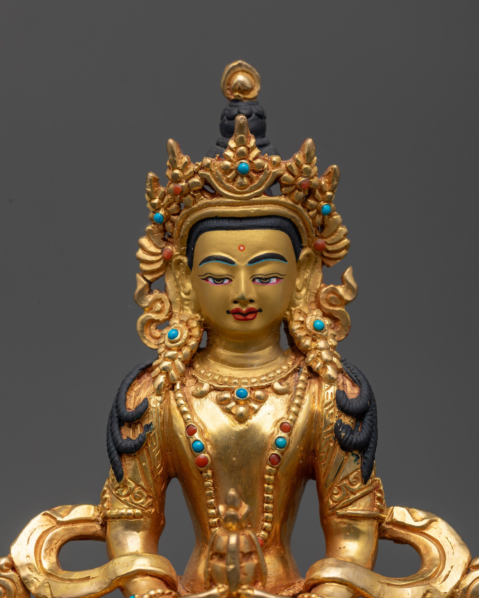 Close up of Amitayus statue showing serene facial expression and nectar vessel
