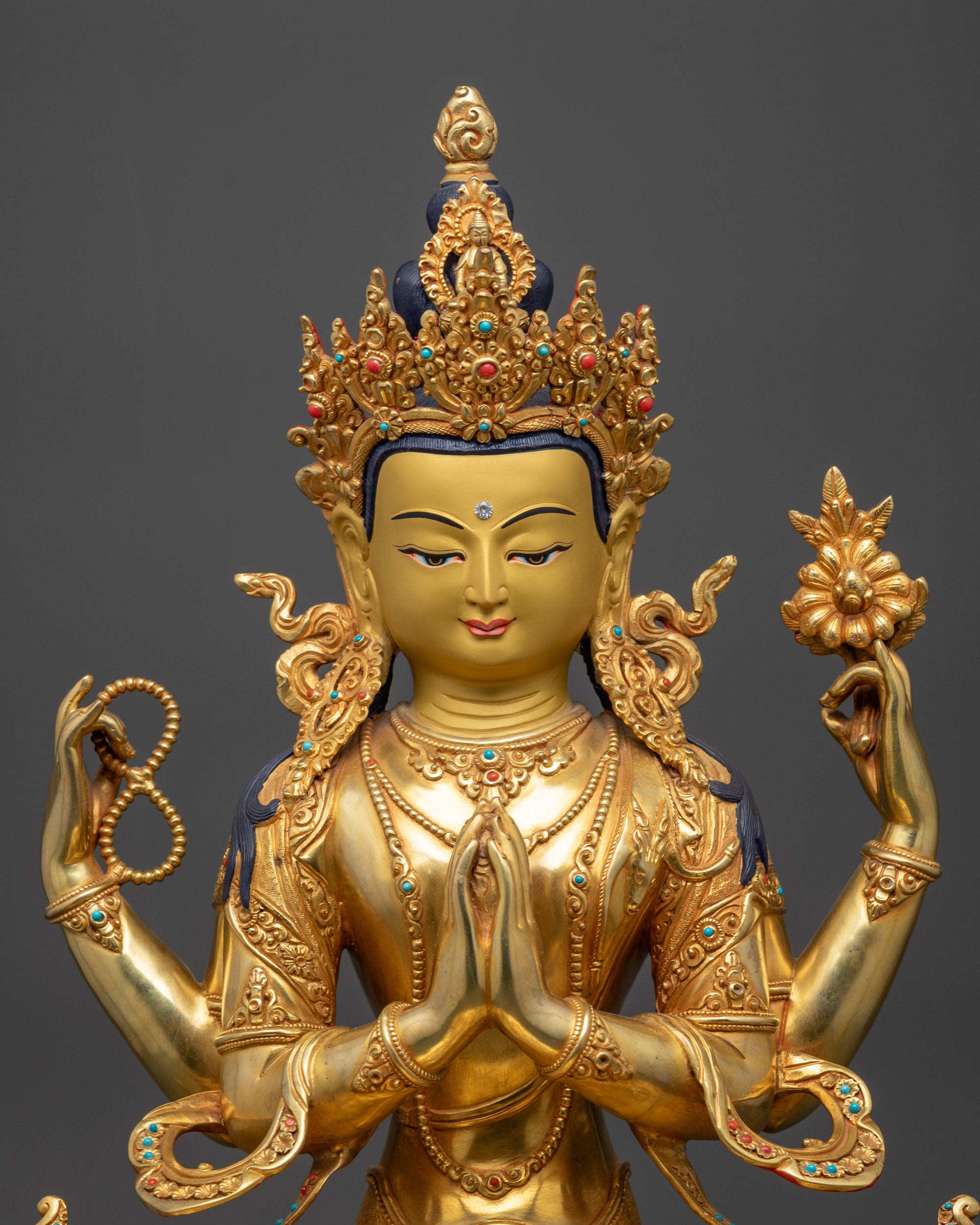 Close up of Chenrezig Statue hands holding gem, upala flower, and crystal rosary