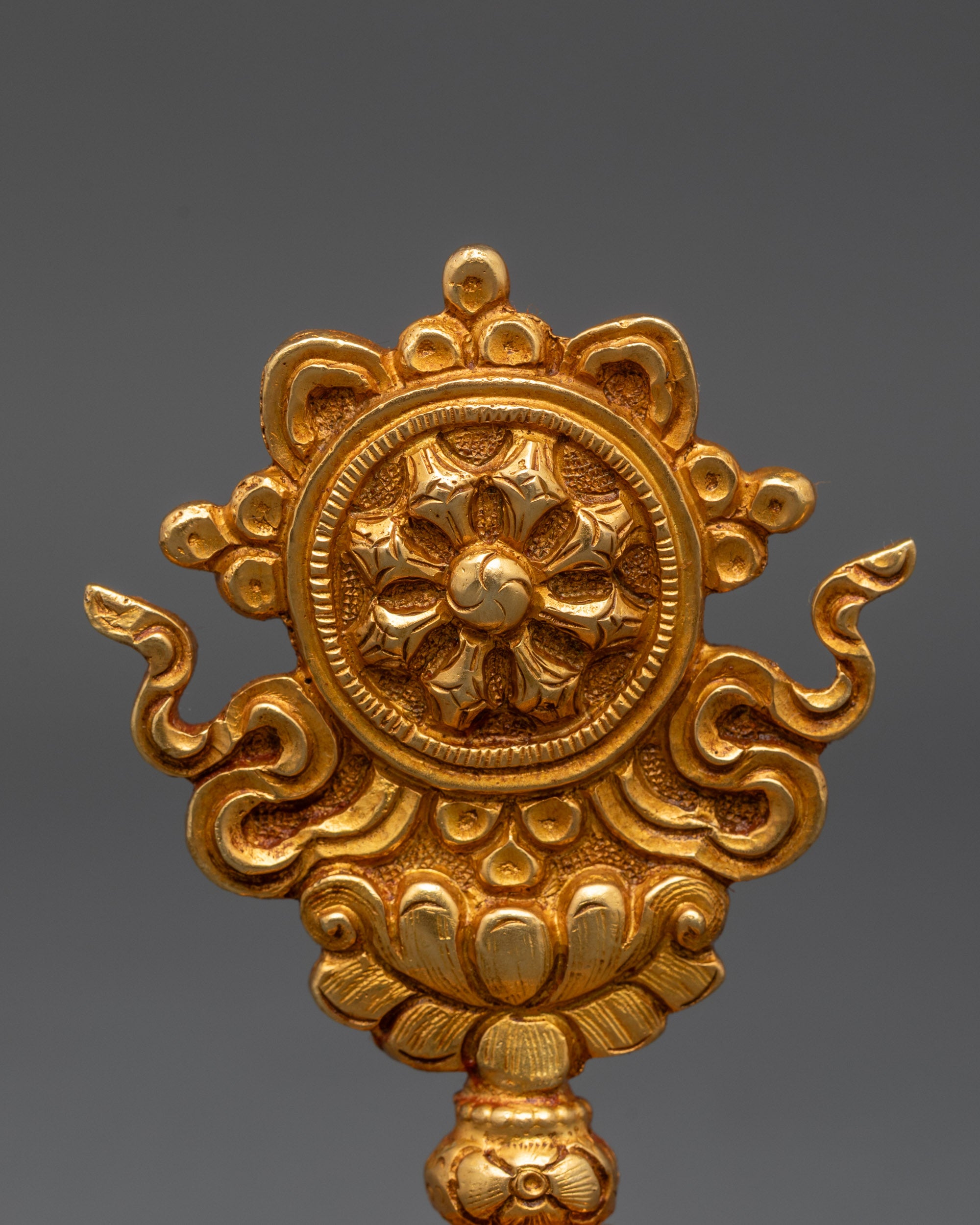 Close up of Dharma Wheel symbol from gold-gilded Buddhist auspicious set