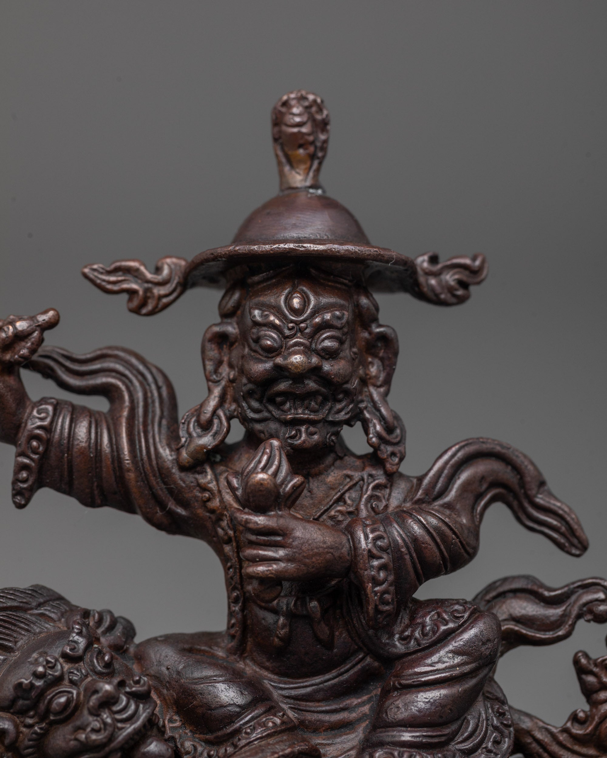 Close up of Dorje Lekpa statue’s oxidized copper face, intricate carvings, and radiant halo