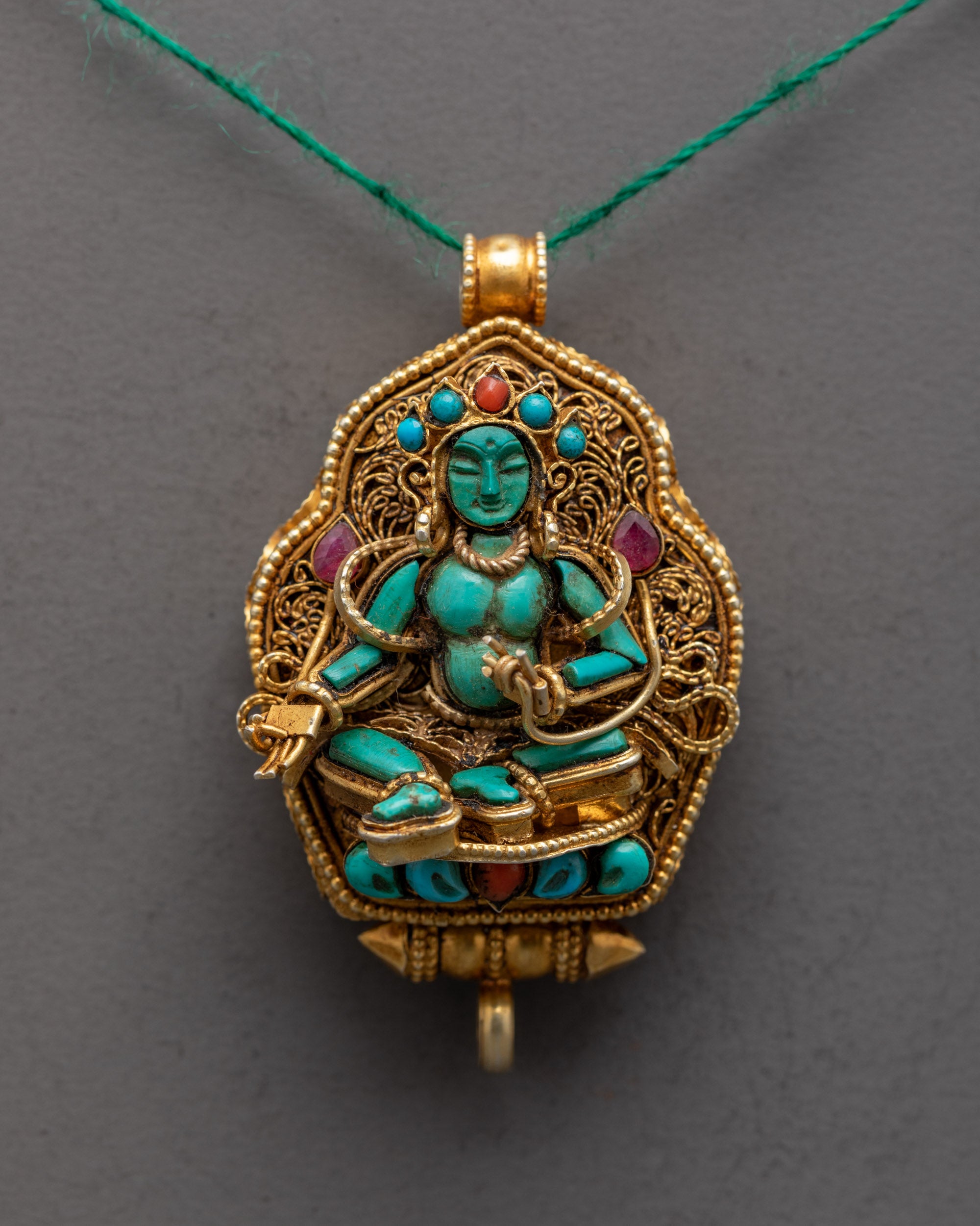 Close up of Green Tara holding utpala flower on gold-plated locket with semi-precious stones