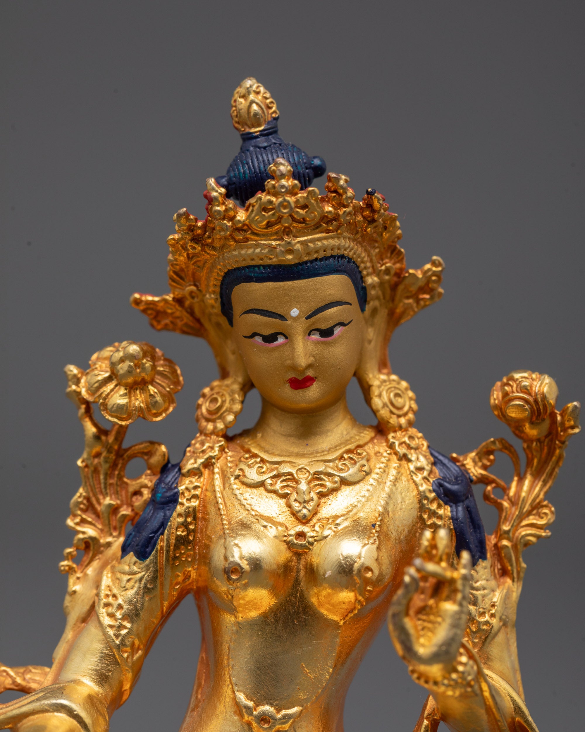 Close up of Green Tara’s precision-carved five-jeweled crown and intricate jewelry details