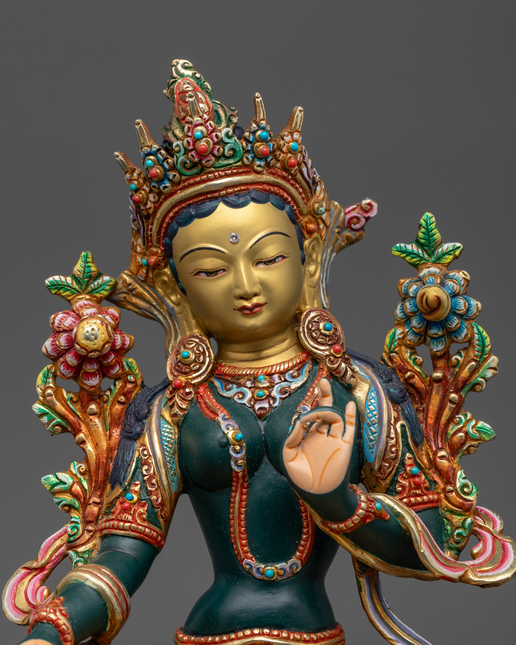 Close up of Green Tara’s serene expression and five-jeweled crown with gold-plated garments