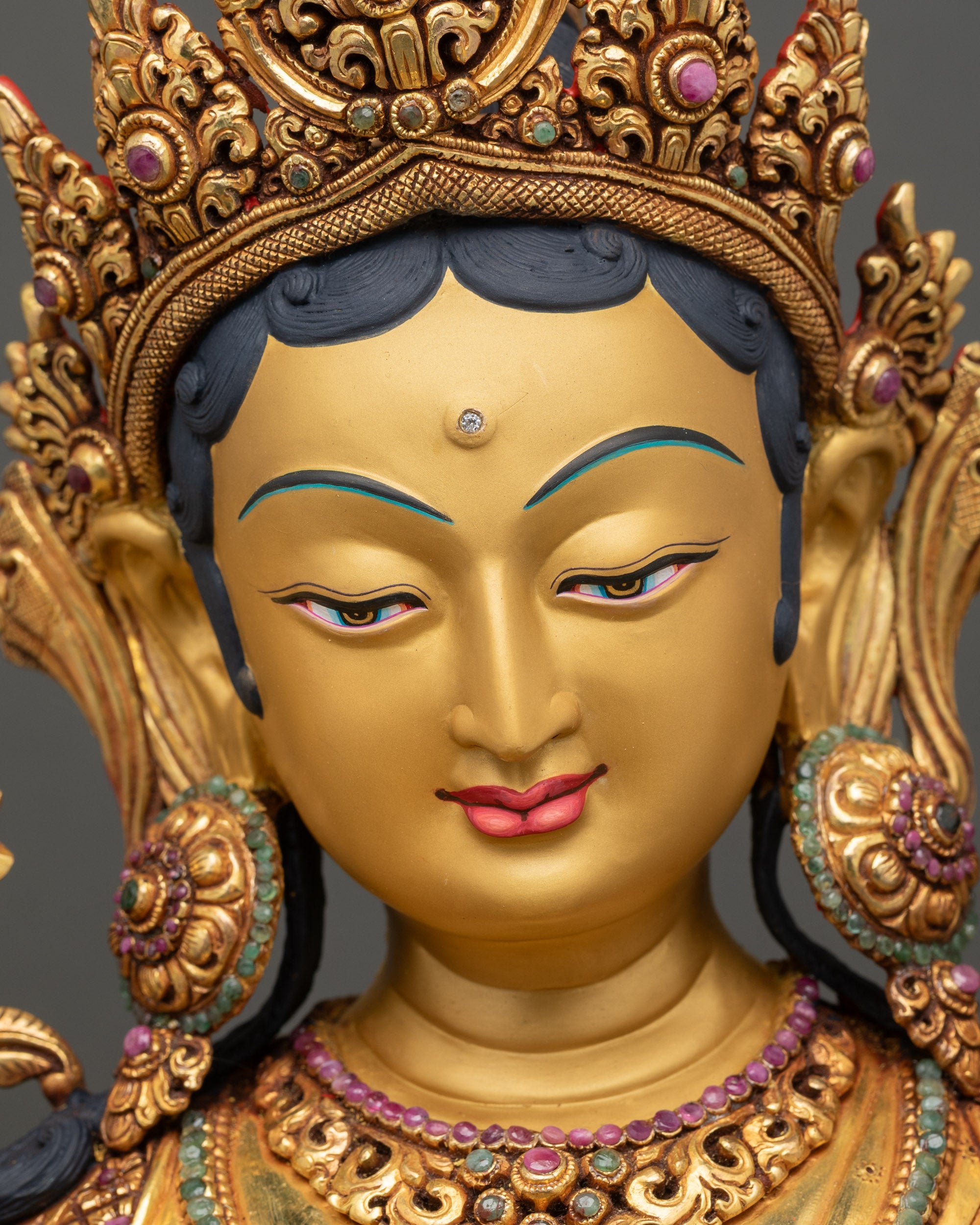 Close up of Green Tara’s serene face with blooming utpala flower beside her shoulder