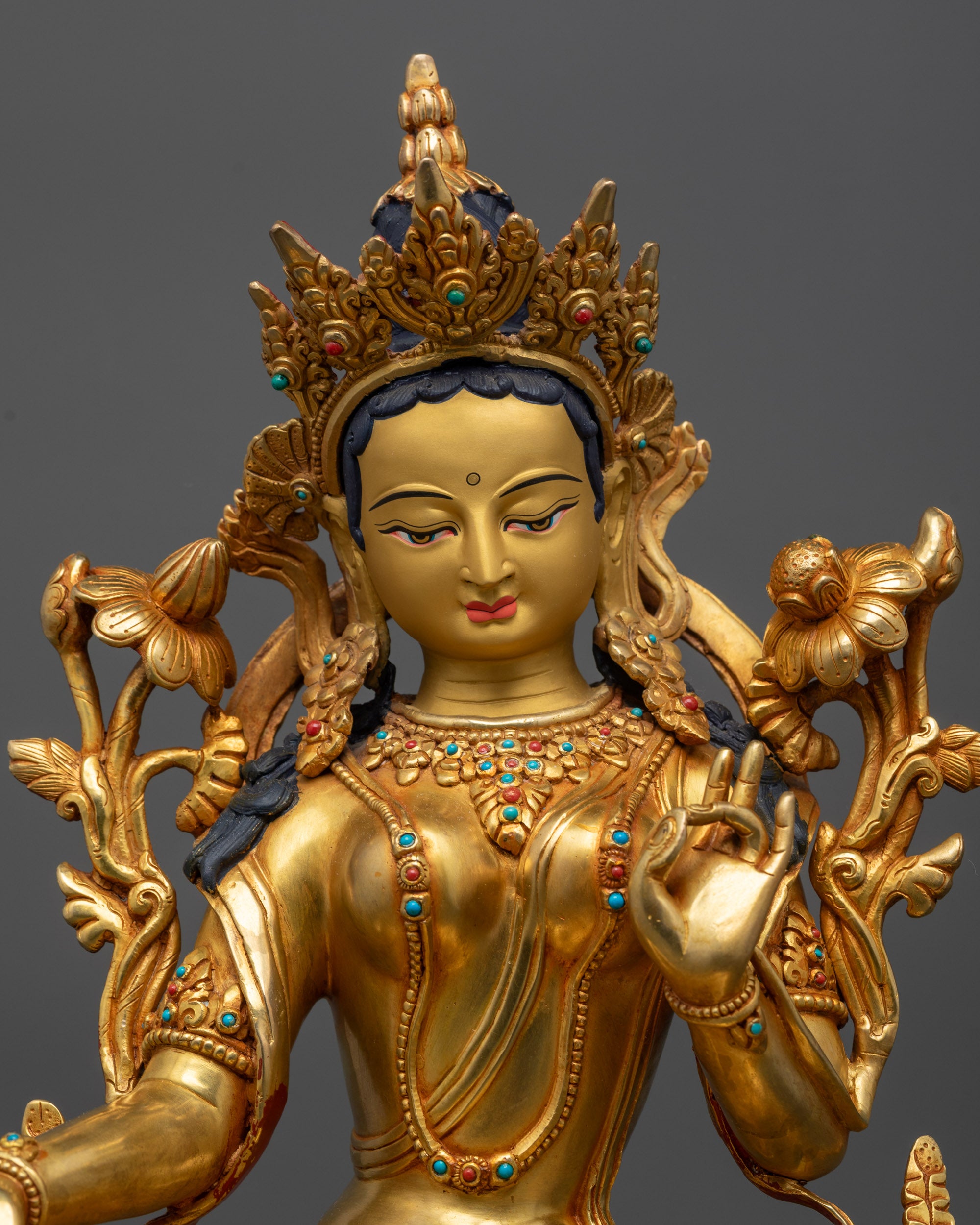 Close up of Green Tara statue showing utpala flower, five-jeweled crown, and jewelry