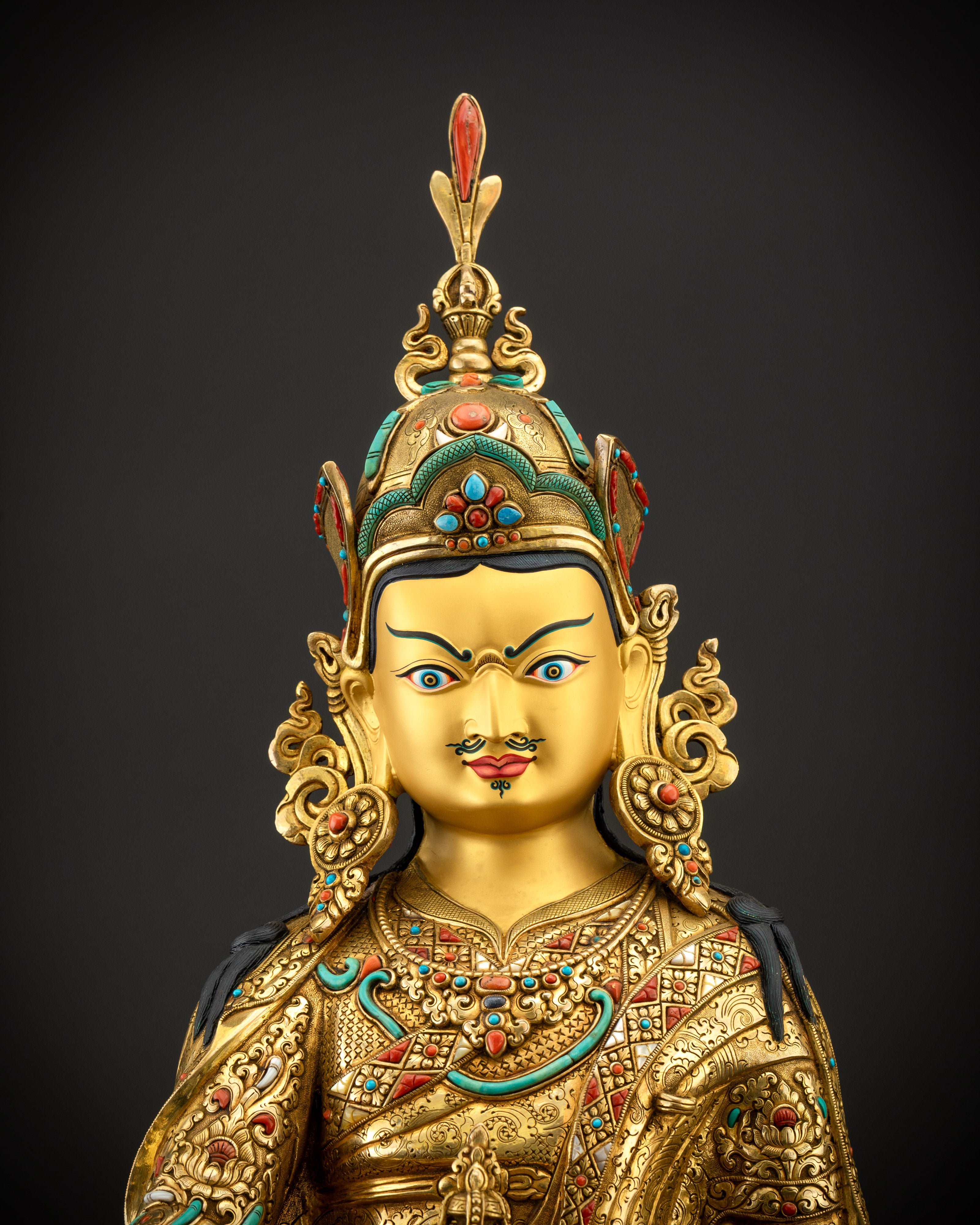 Close up of Guru Padmasambhava face with gold-gilded details and gemstone inlays