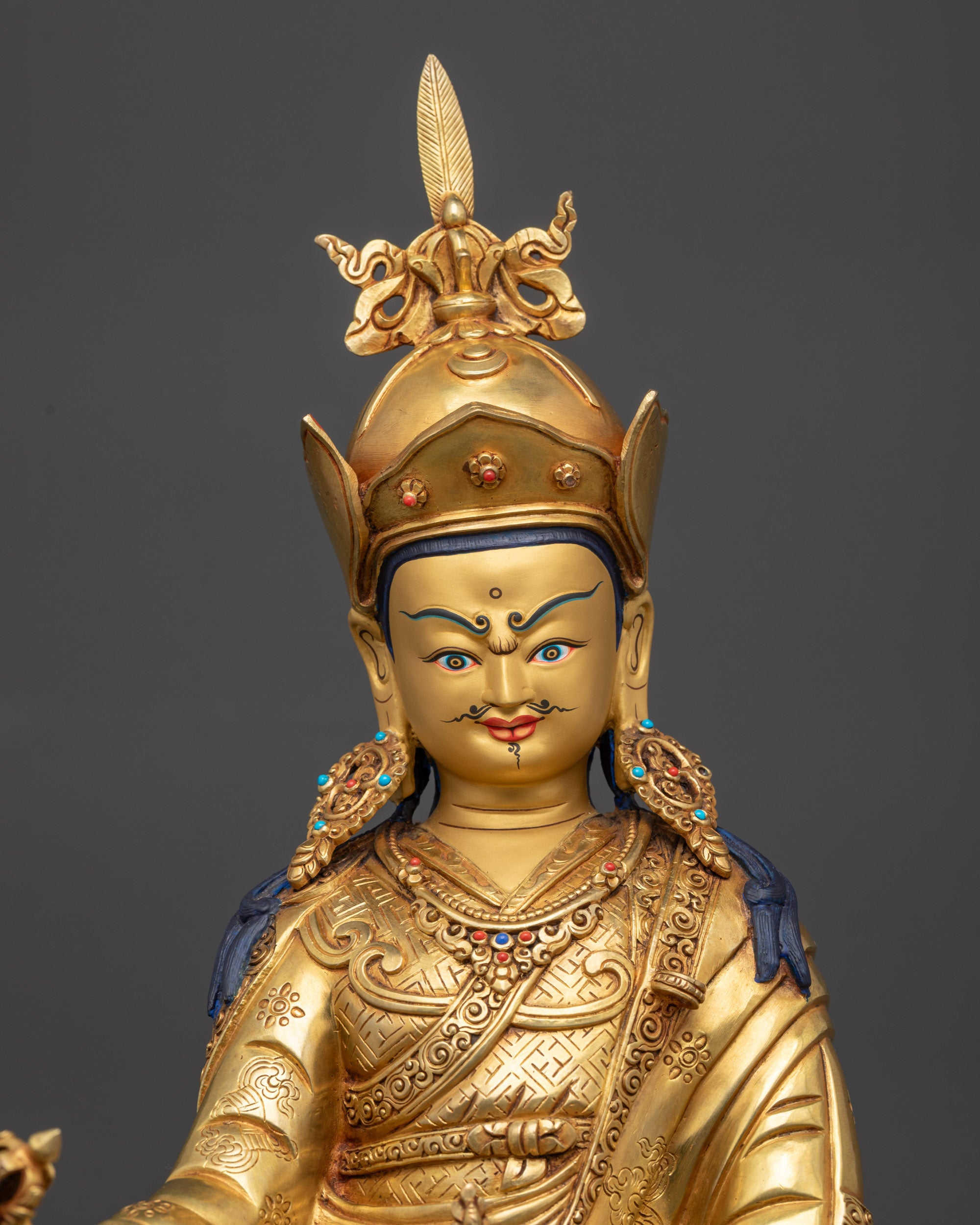 Close up of Guru Rinpoche statue highlighting skull cup, dorje, and lotus hat