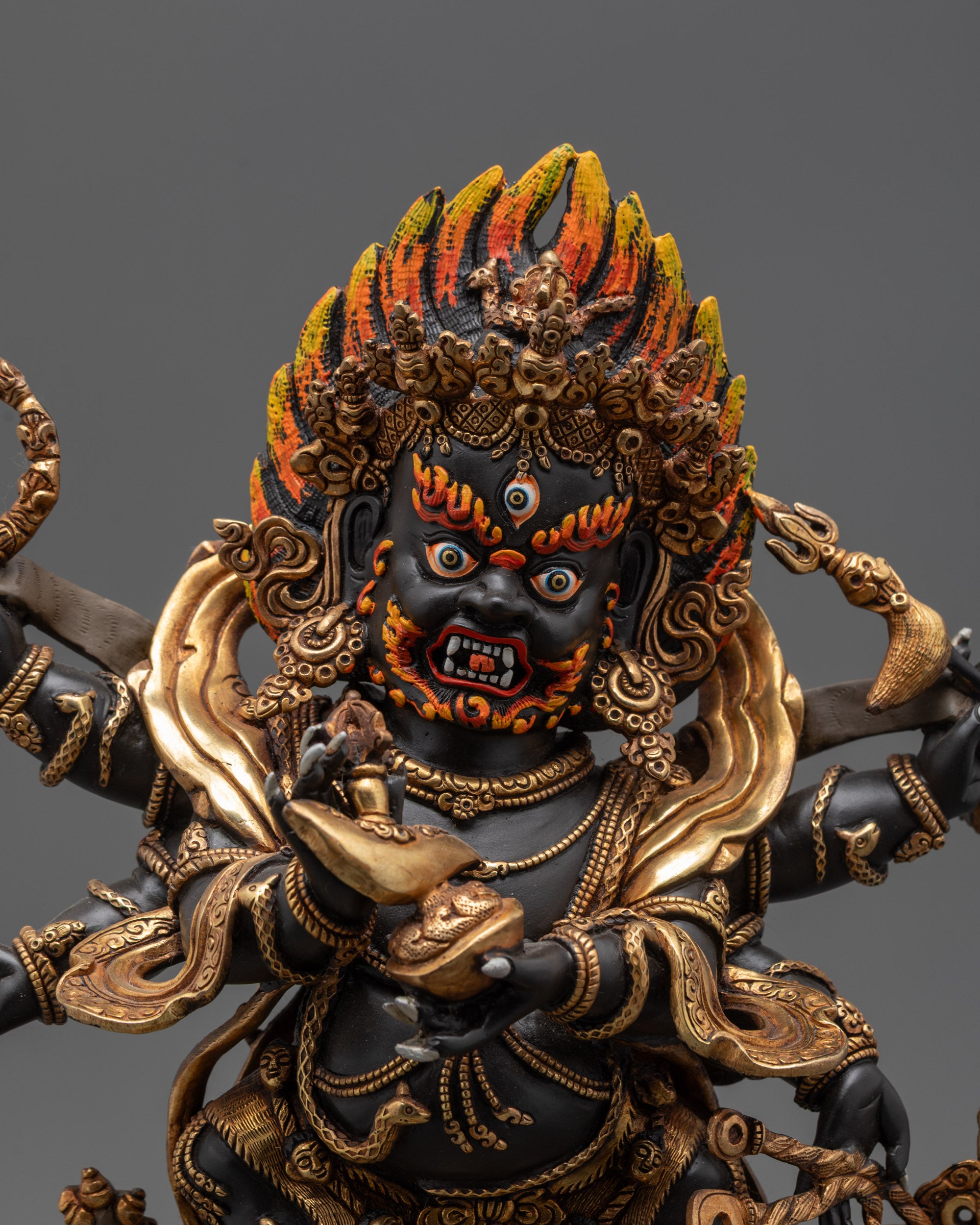 Close up of Mahakala crown, skull garland, and sacred objects in six arms