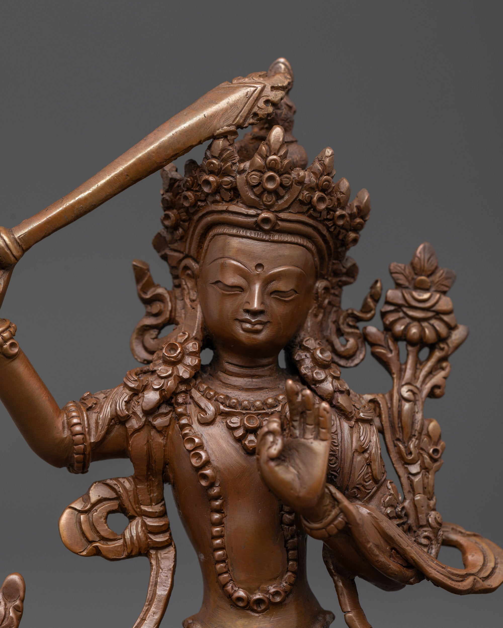 Close up of Manjushri Sculpture showing Abhaya mudra and intricate oxidized copper details