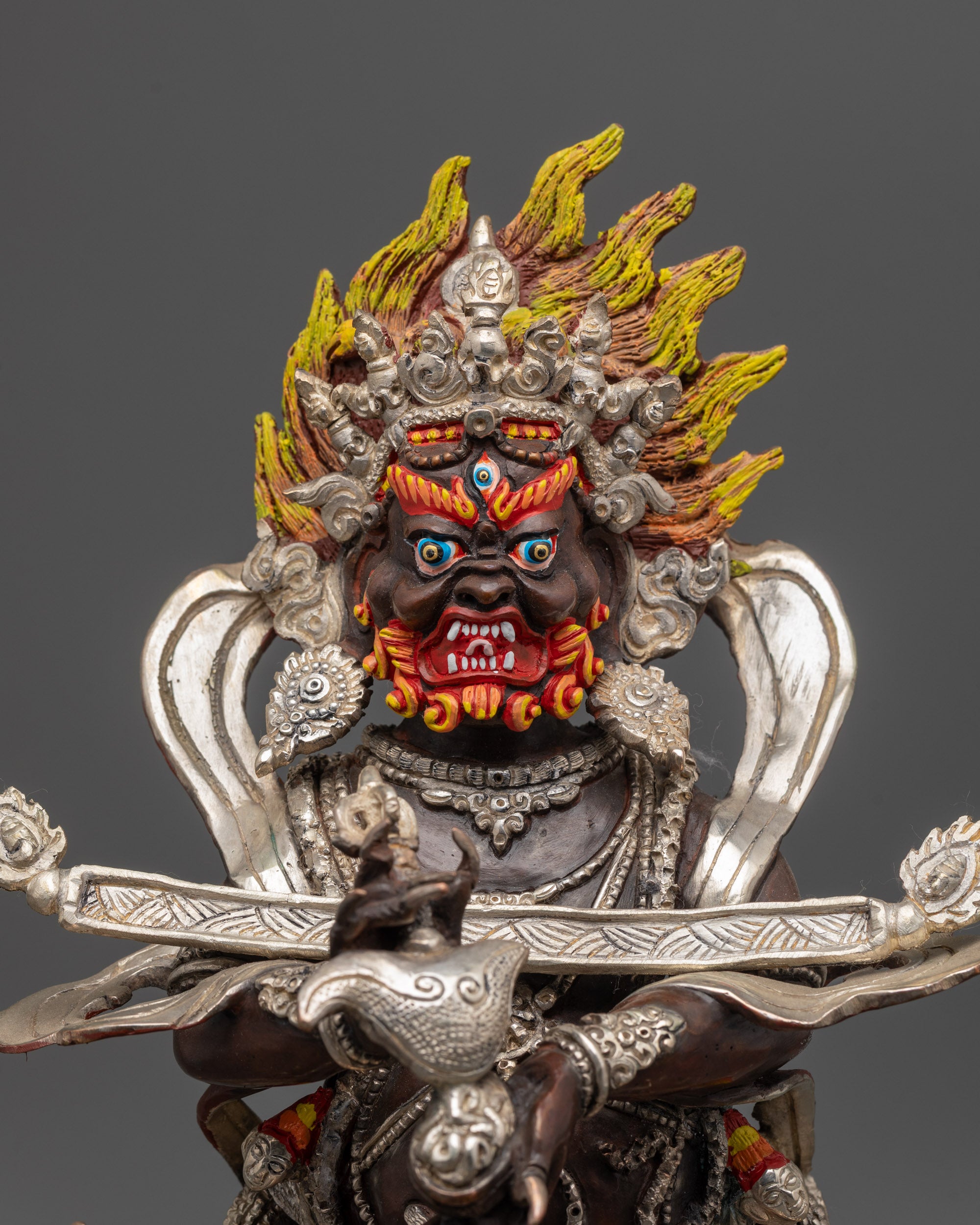 Close up of Sakya Mahakala’s five-skull crown and kartika knife with silver accents