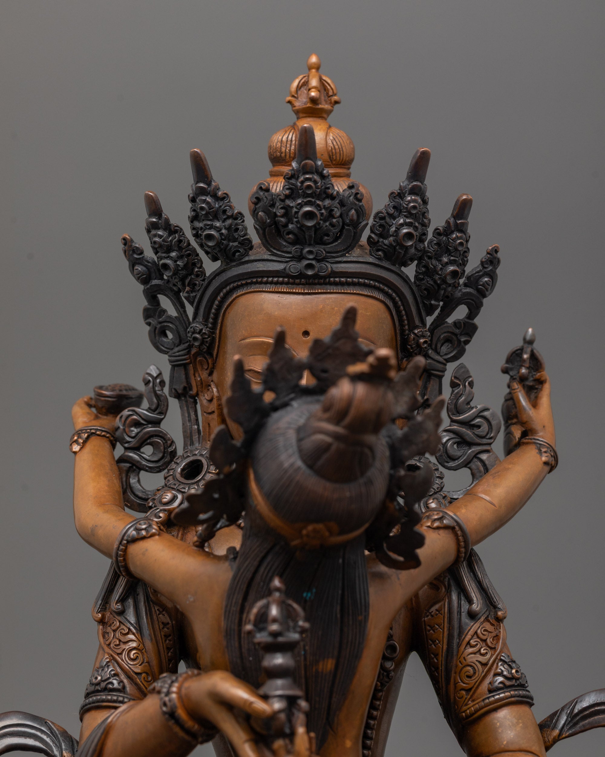 Close up of Vajrasattva’s vajra and bell in oxidized copper with rich patina finish