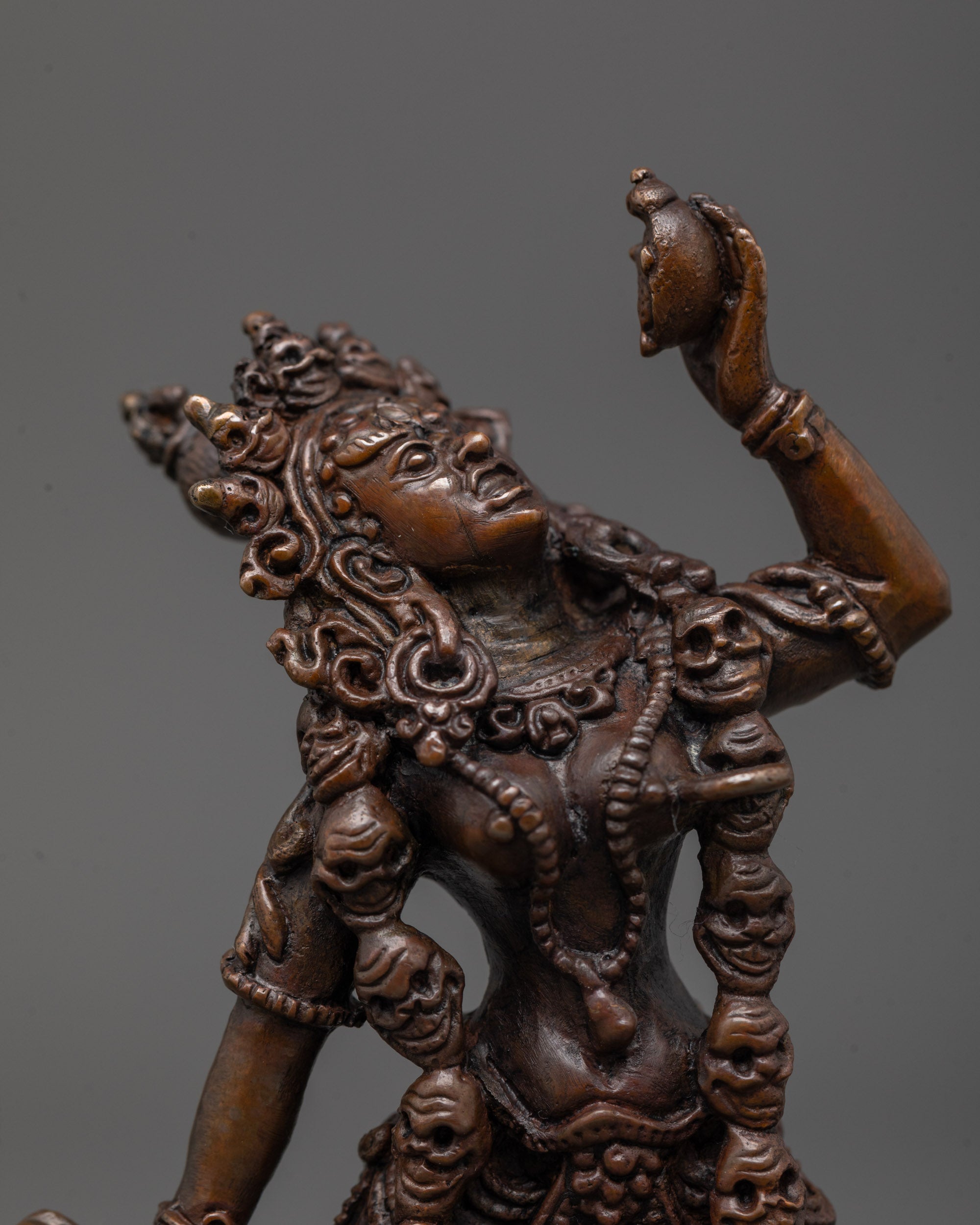 Close up of Vajrayogini’s skull crown and Mundamala garland on oxidized copper statue