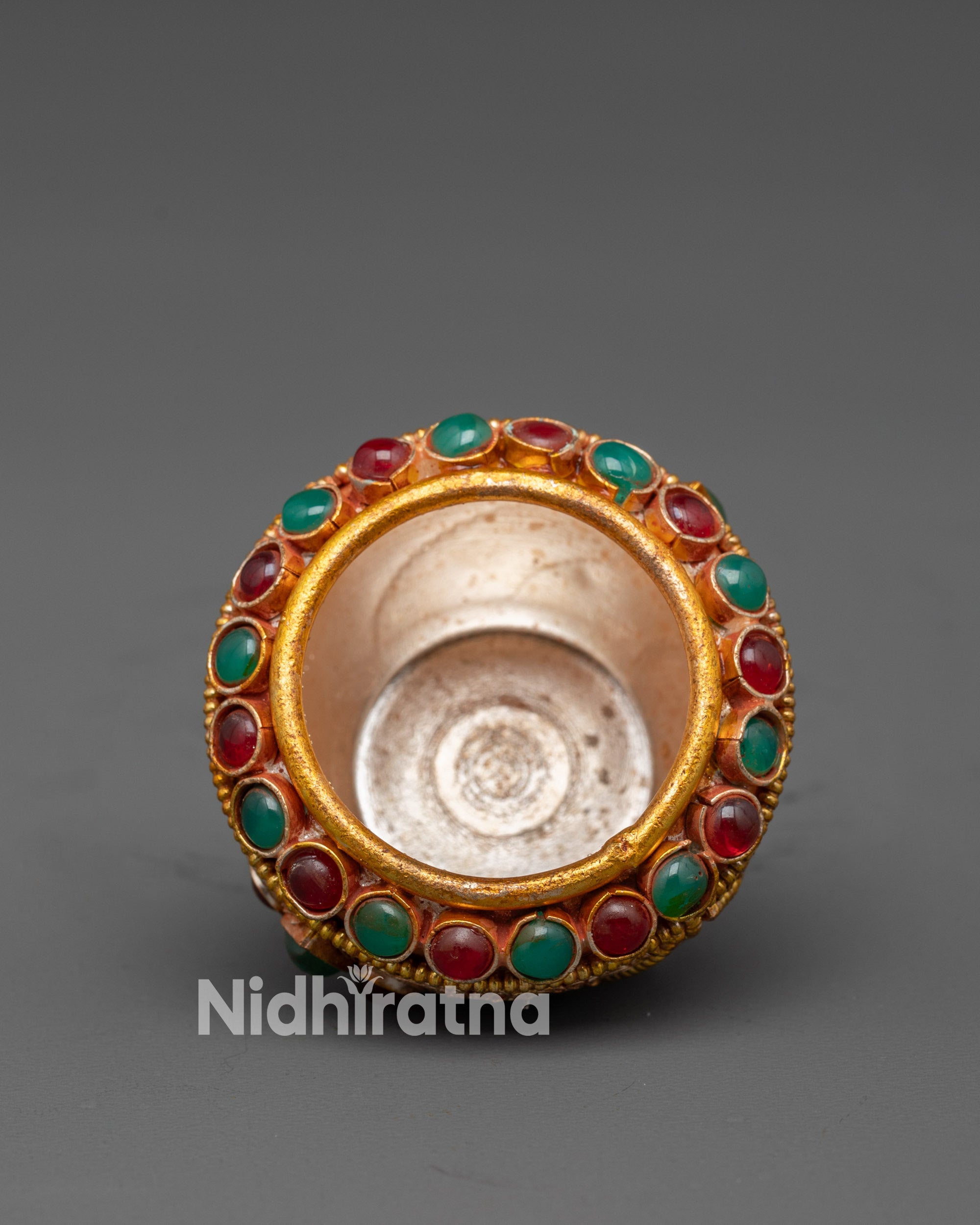 Close up of deity figure and semi-precious stones on Tibetan Golpa bowl