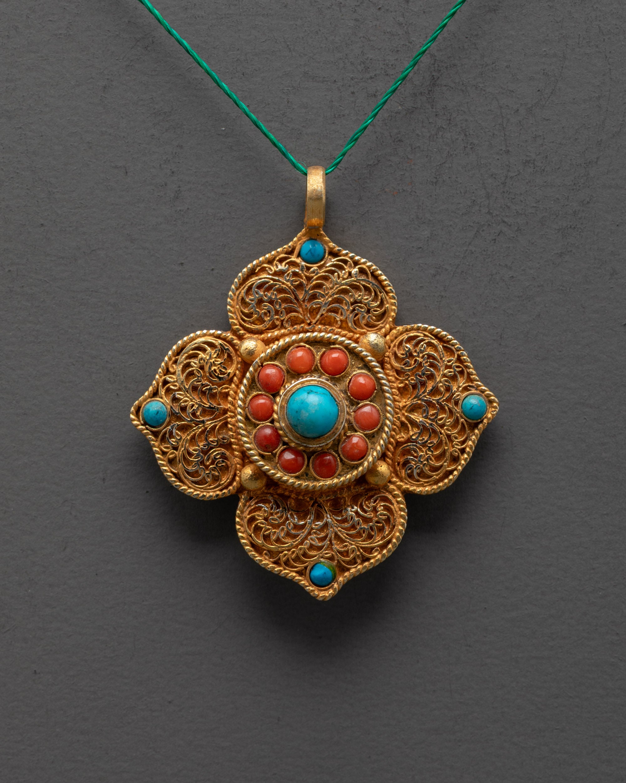 Close up of gold-plated lotus locket filigree design and turquoise center stone